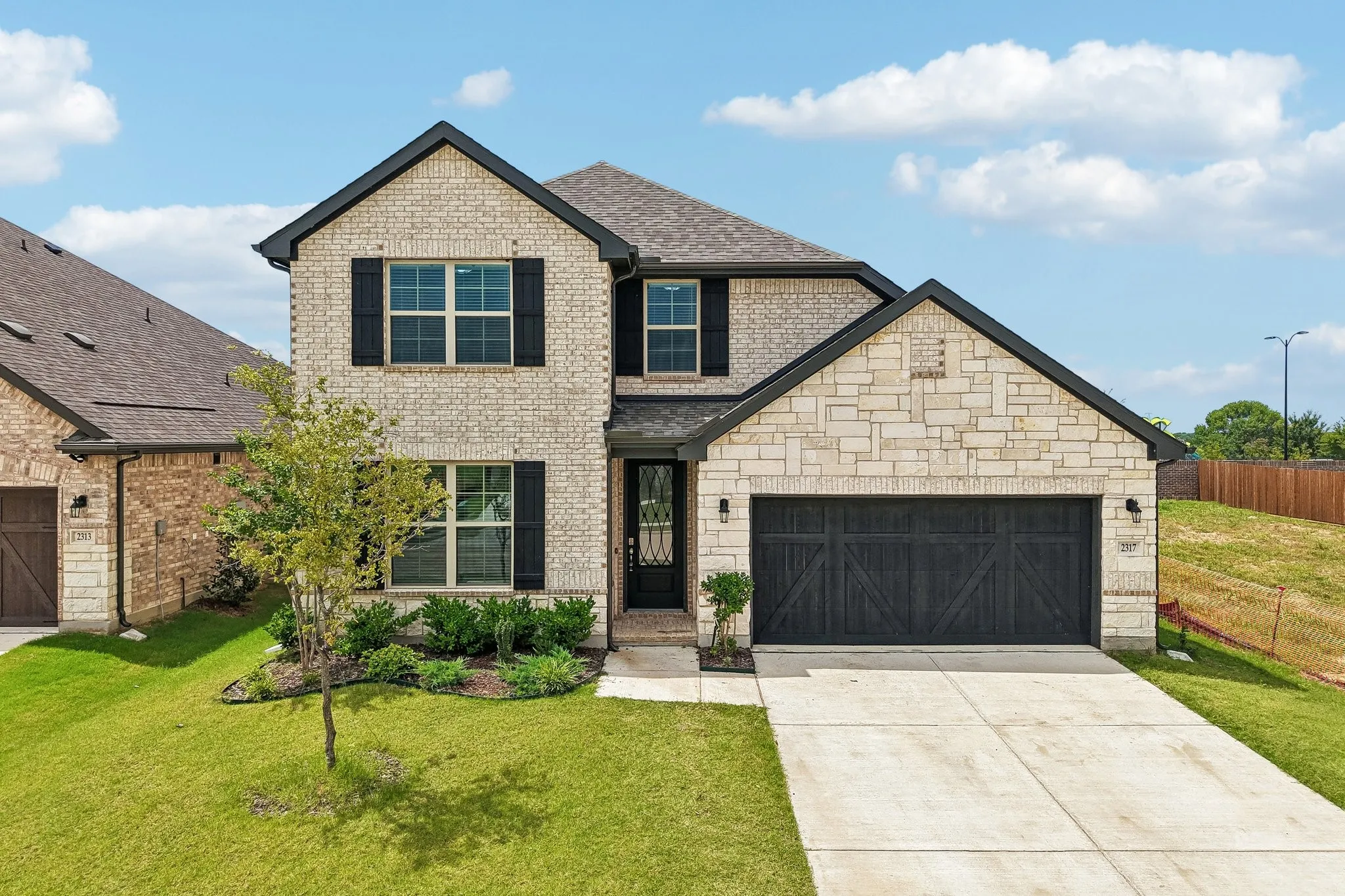 Two-story residence featuring a light brick exterior with dark trim and shutters