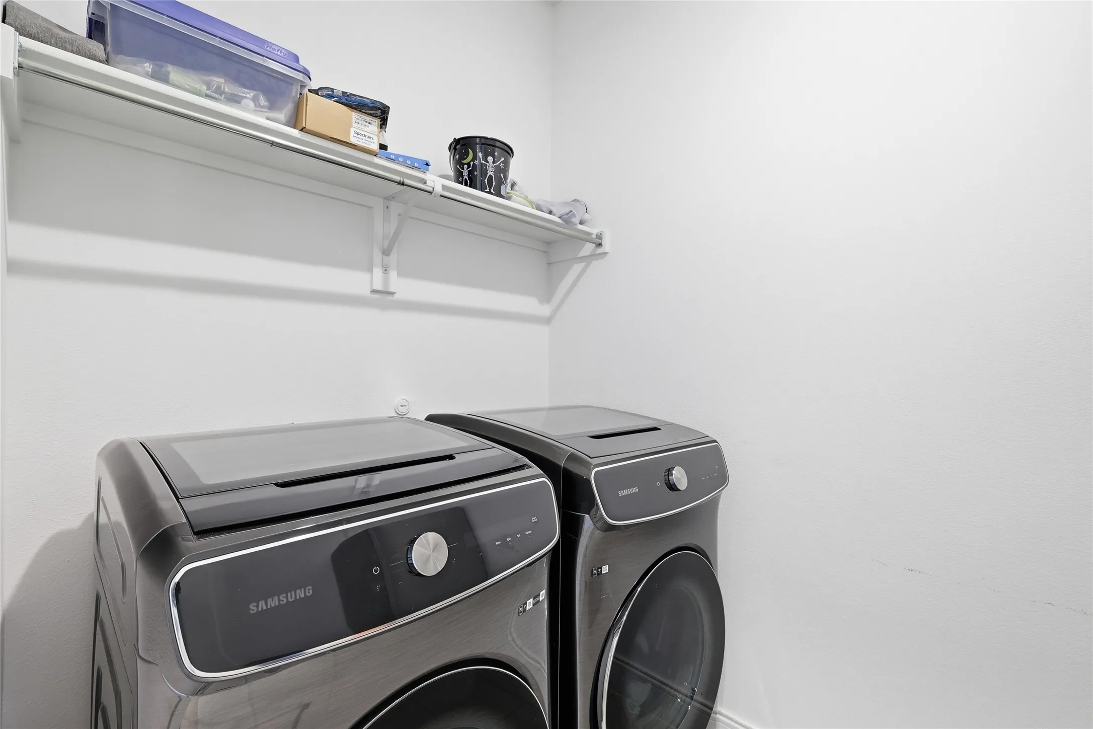 Laundry area with upper white shelving