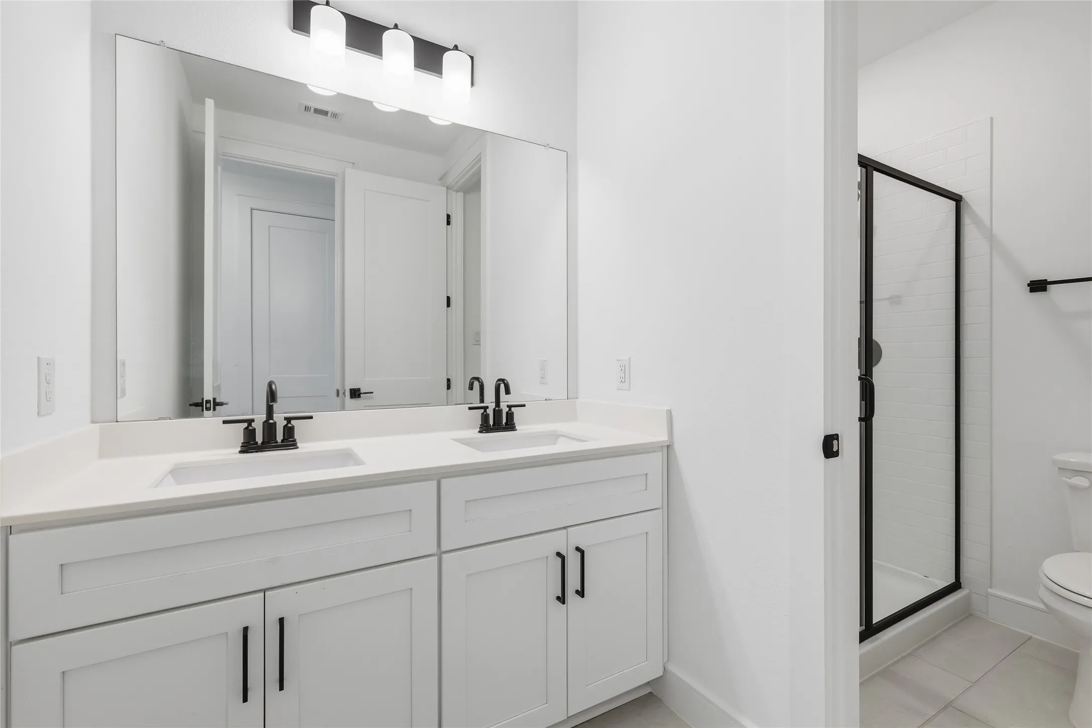 White dual vanity with integrated sinks, quartz-finish countertop, and matte black fixtures