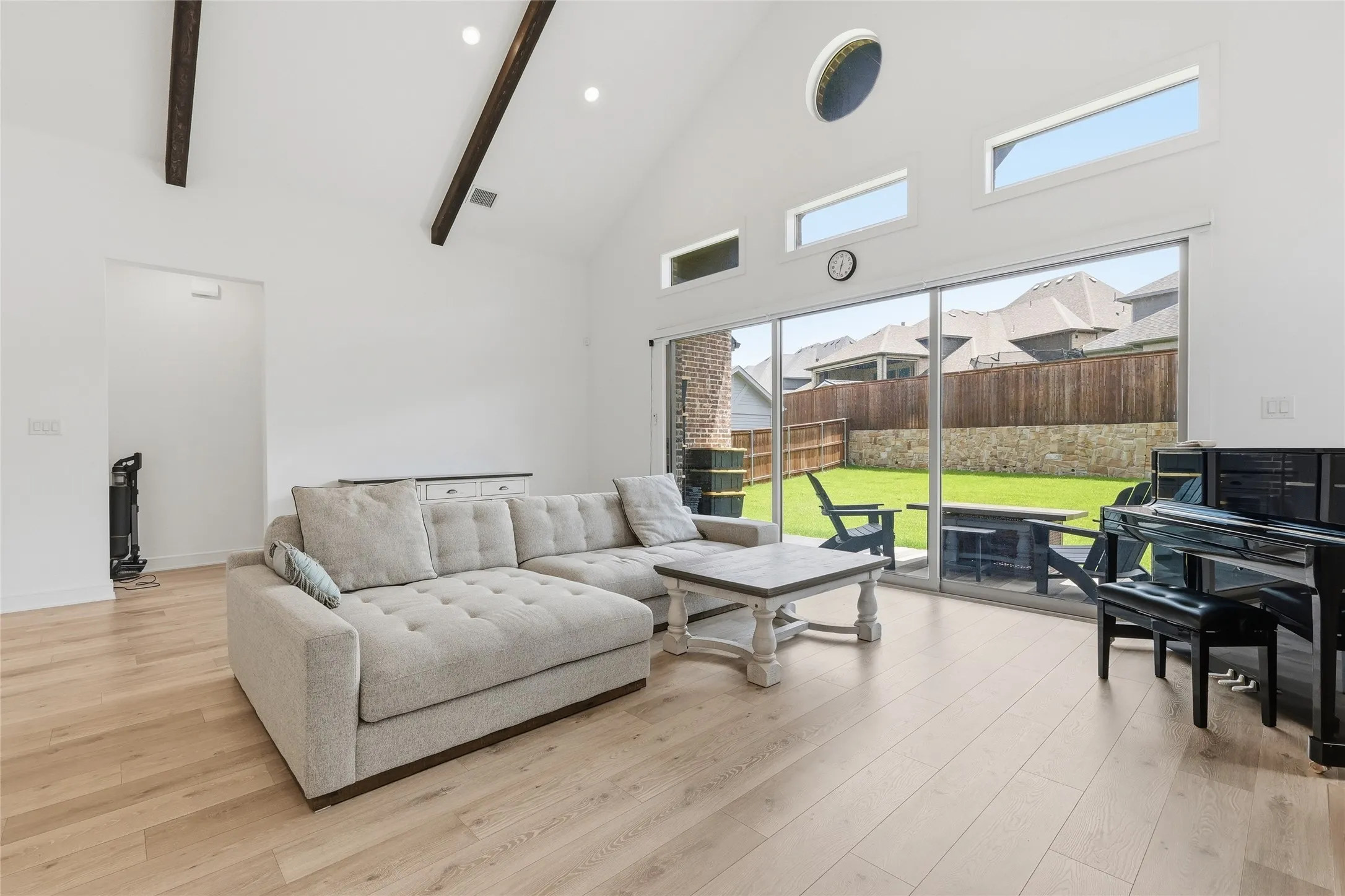 Vaulted ceilings with exposed wood beams, expansive sliding glass doors, and light wood-finish flooring