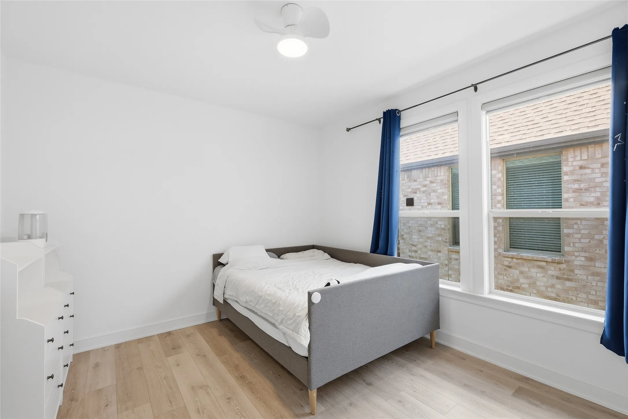 Bright room featuring light wood-finish flooring and a ceiling fan with integrated lighting