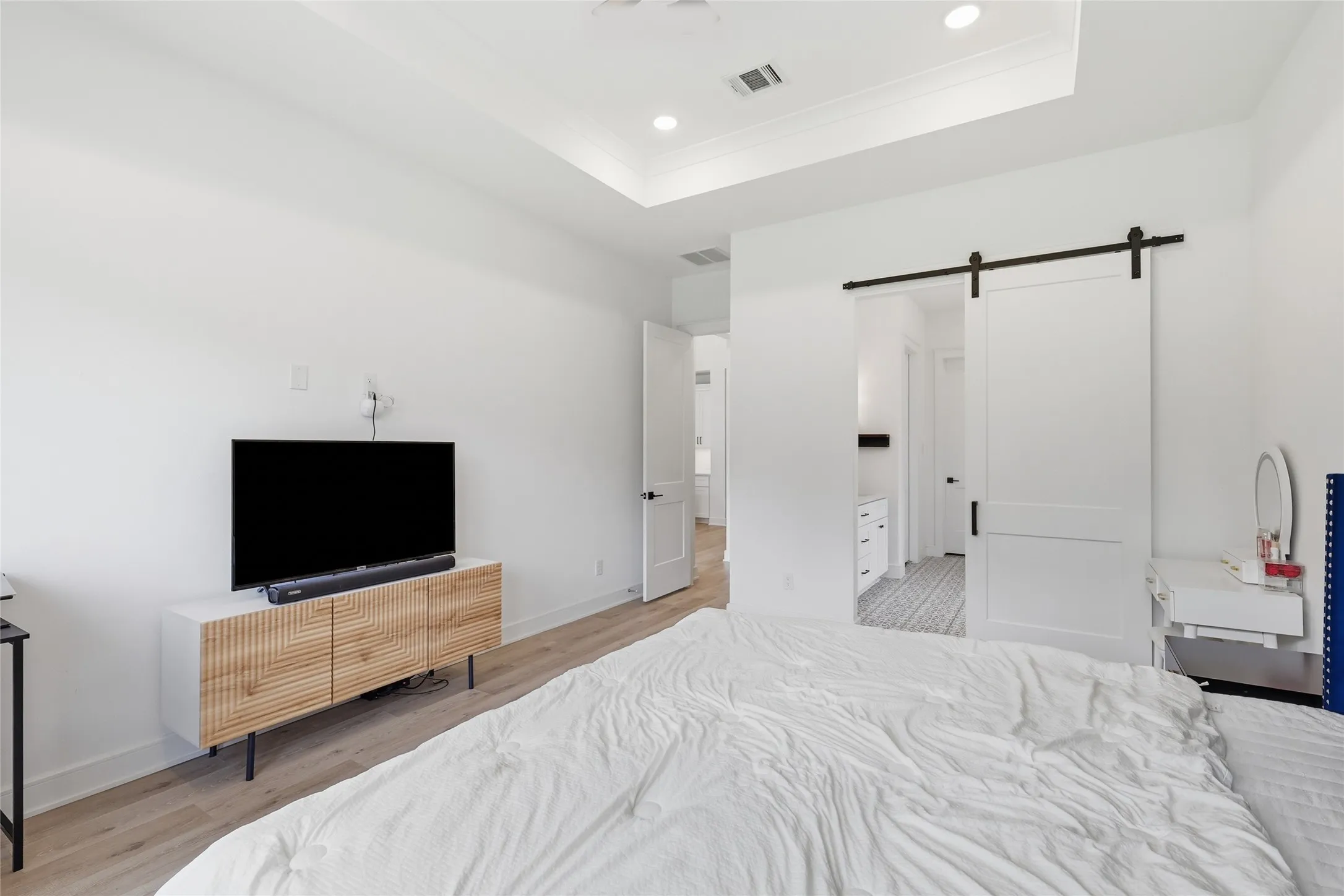 Bright interior featuring wood-finish flooring, a tray ceiling with recessed lighting, and a modern barn door entry
