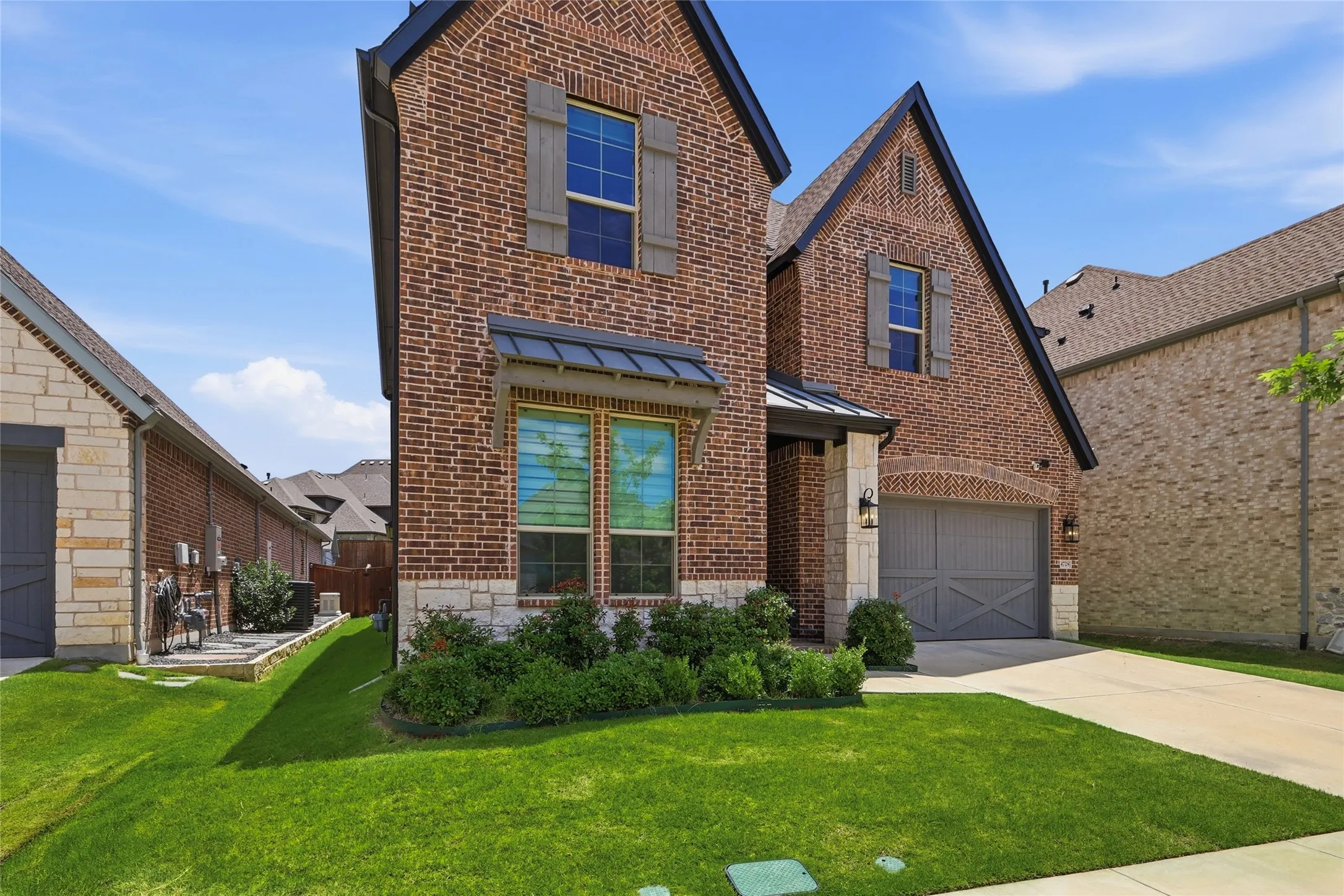 Brick facade with stone accents, a two-car garage, and a manicured lawn