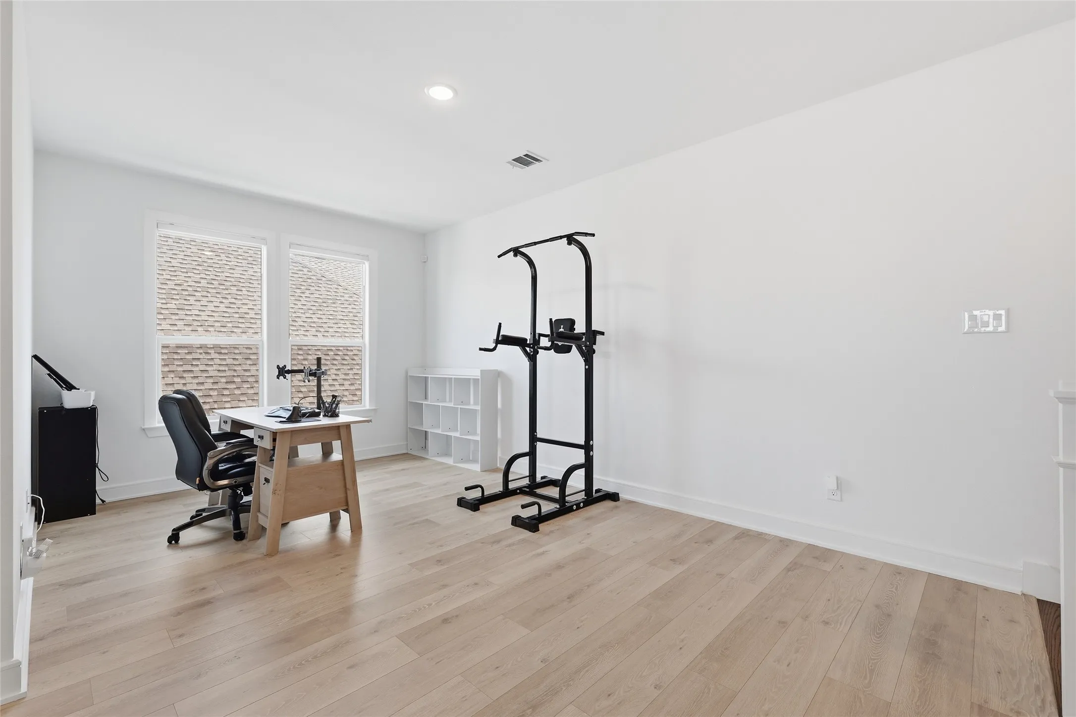 Light-filled room featuring wood-finish flooring, recessed lighting, and bright white walls
