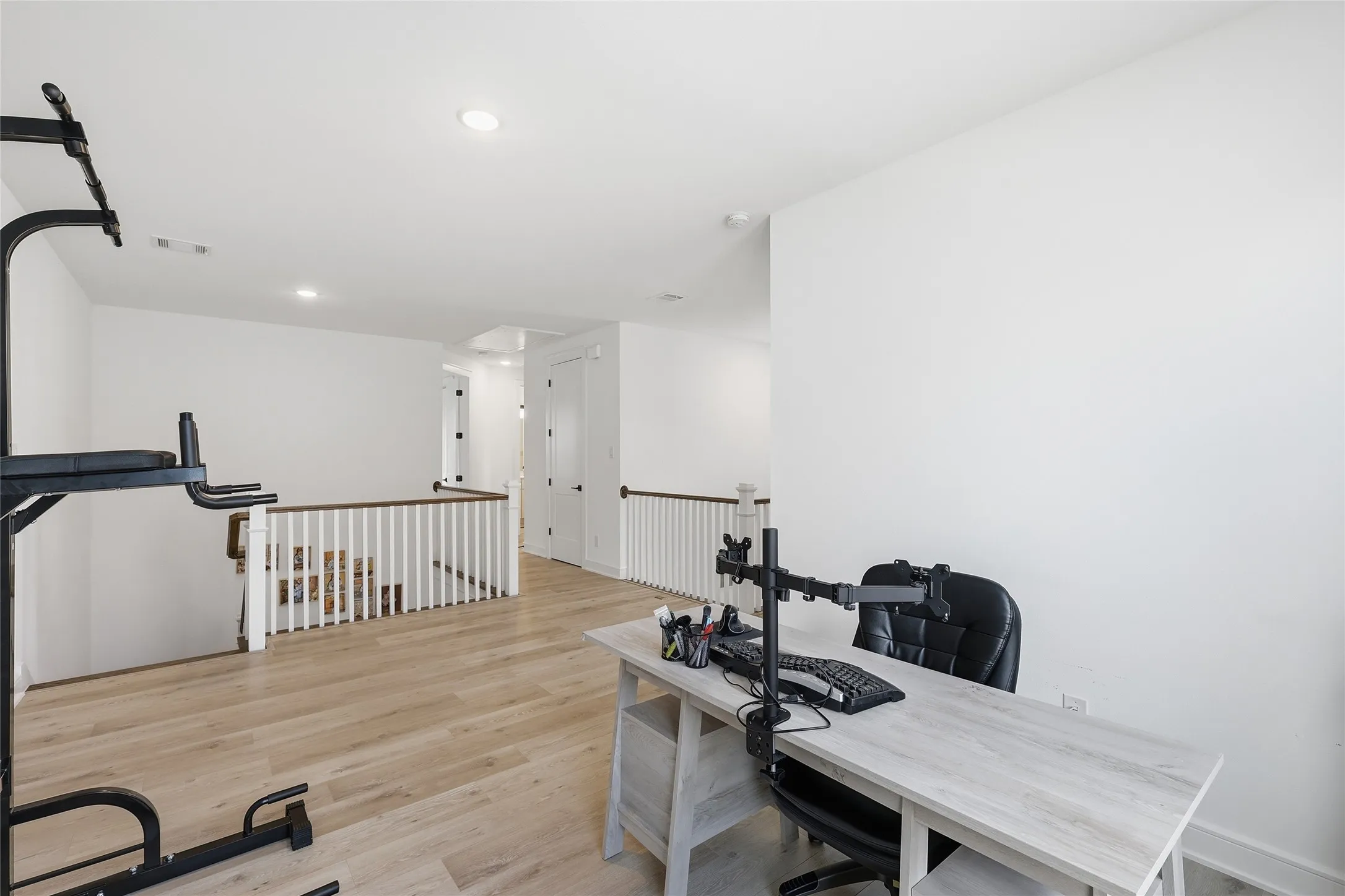 Open concept loft space with wood-finish flooring, recessed lighting, and white walls
