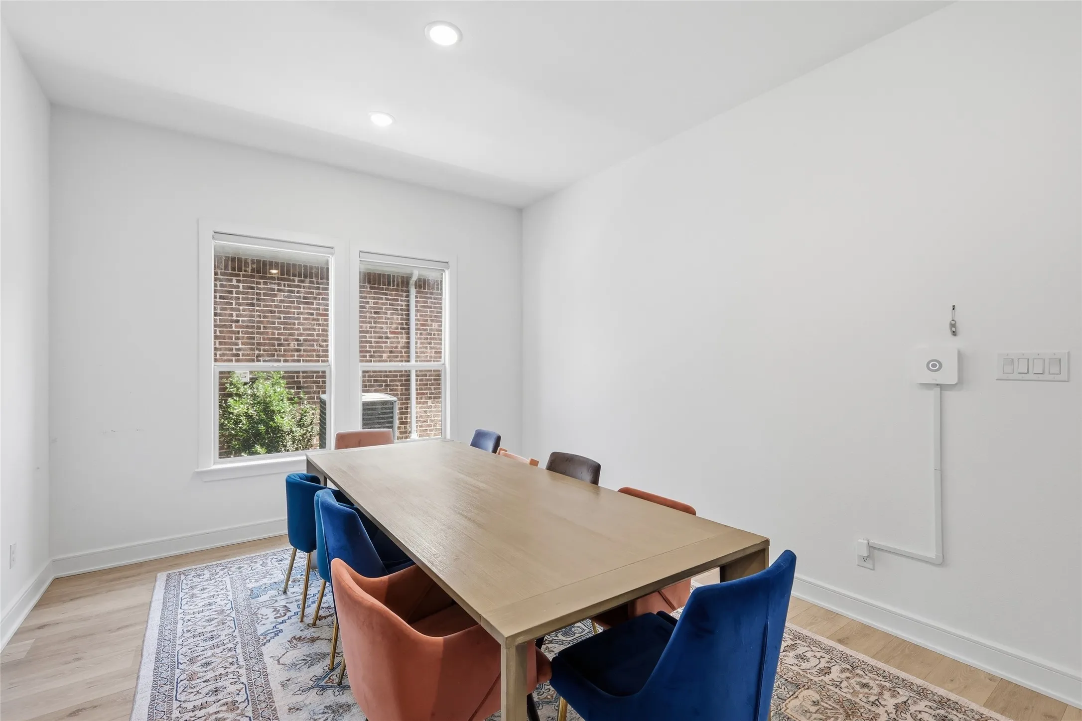Bright interior space featuring a large window with white trim, recessed ceiling lighting, and wood-finish flooring