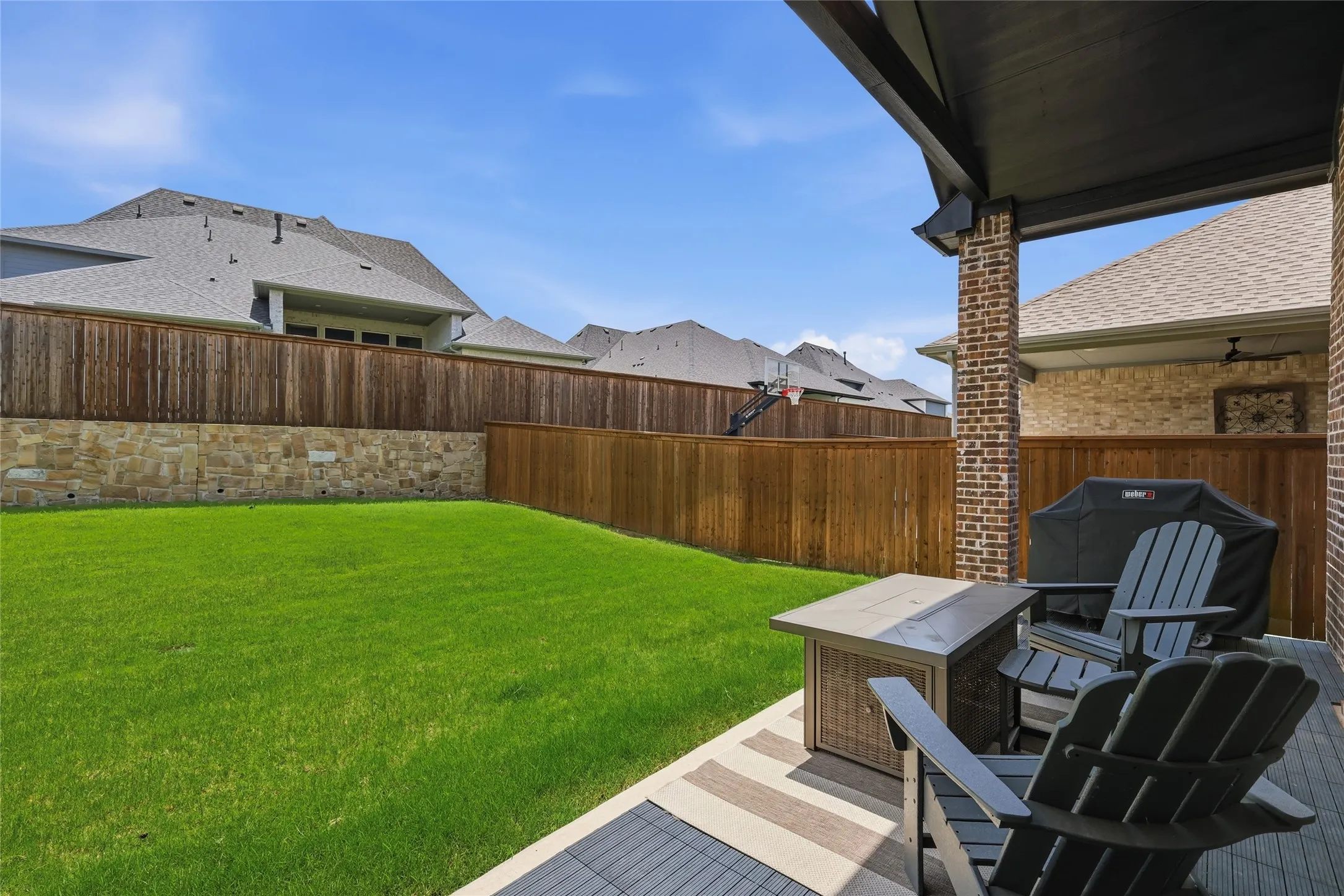 Covered patio featuring a ceiling fan, brick column, and wood-finish decking