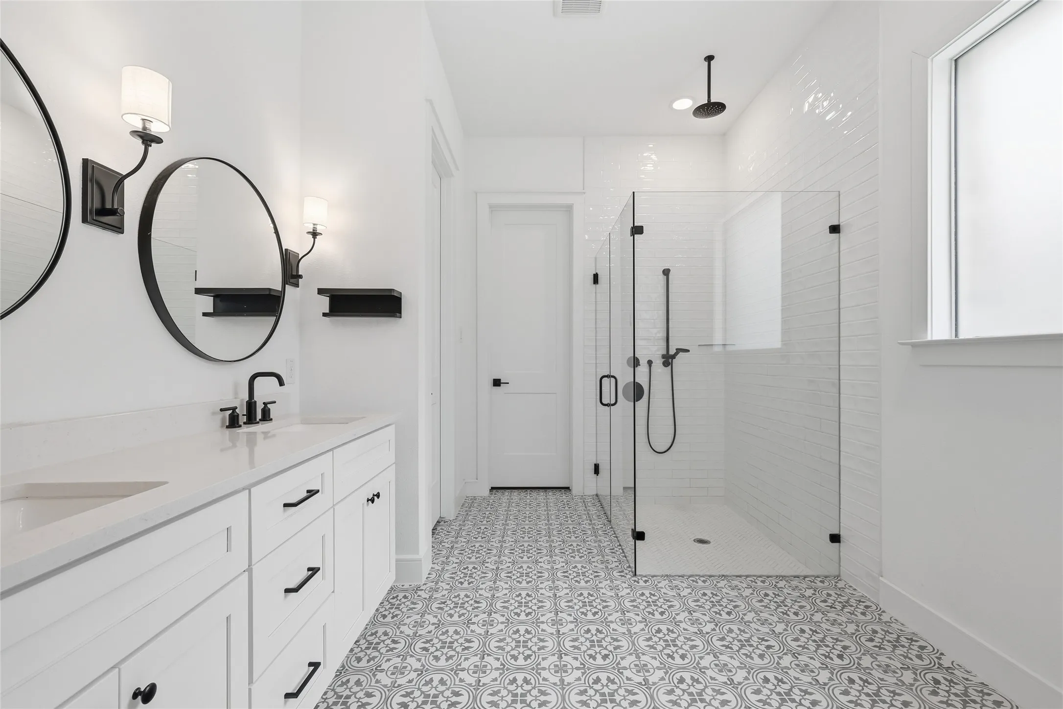 Dual vanity with white cabinetry and integrated sinks, complemented by matte black fixtures and round mirrors