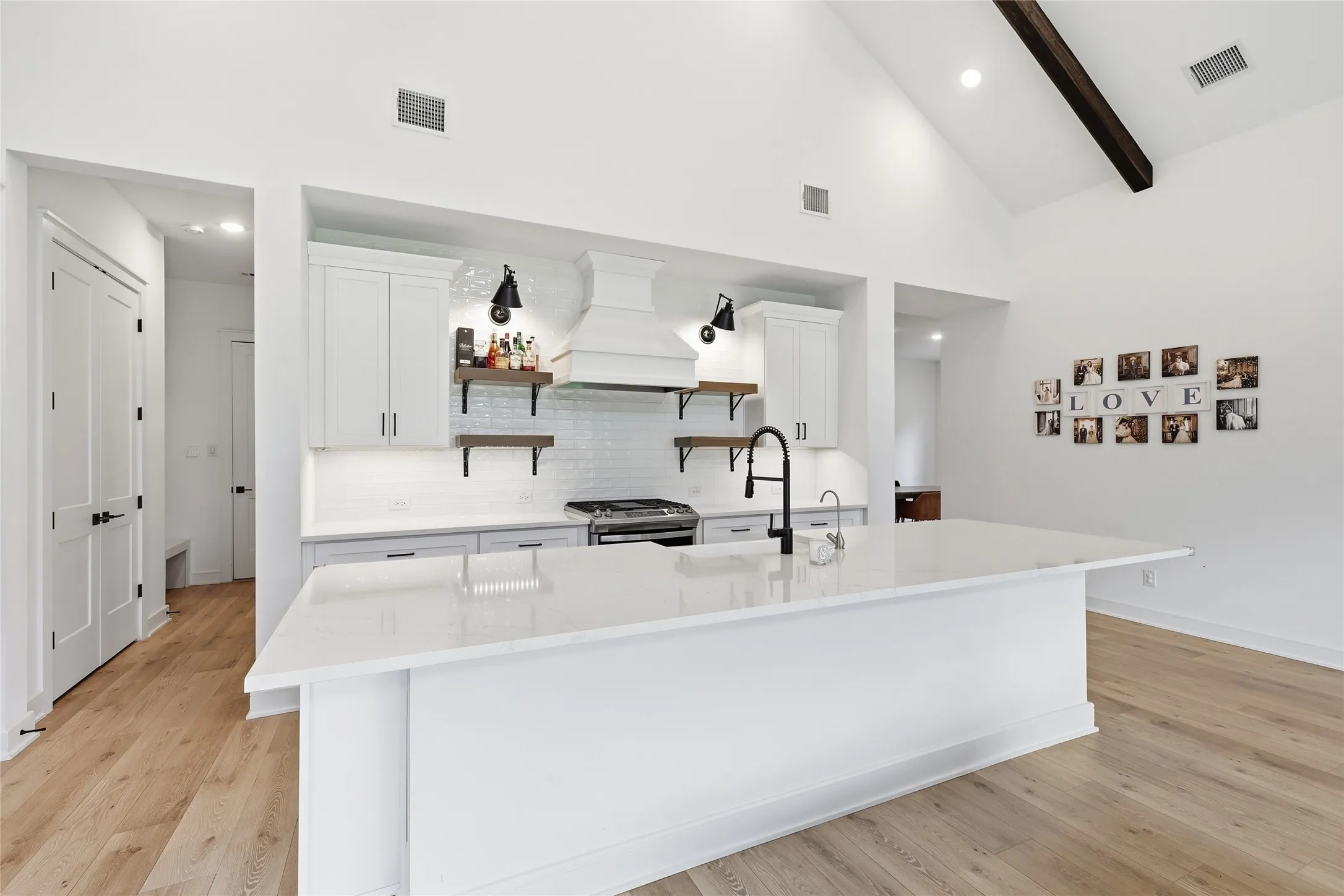 Spacious kitchen featuring a large central island with a matte black faucet, white shaker cabinetry, and a subway tile backsplash