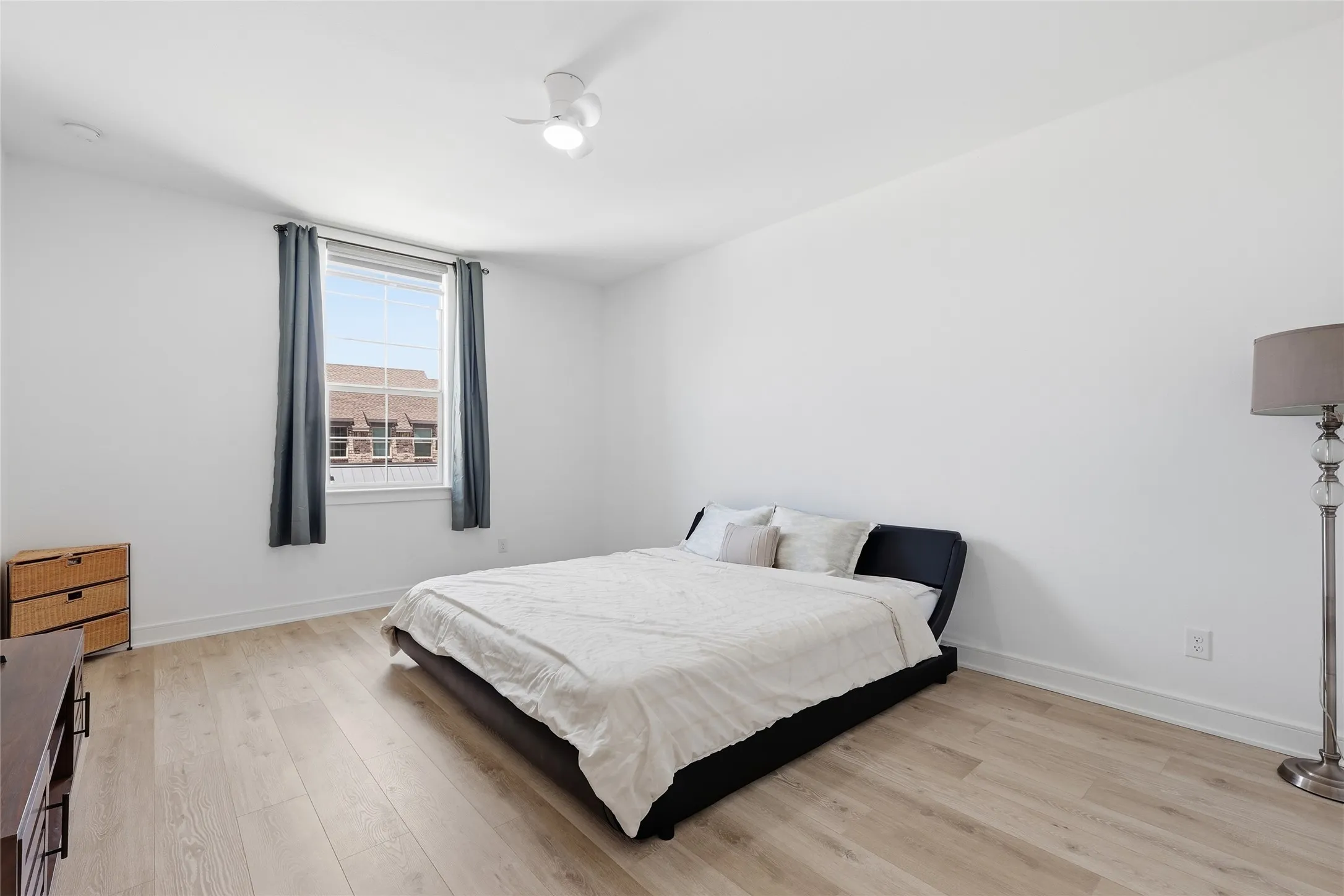 Bright room featuring light wood-finish flooring, white walls, and a ceiling fan