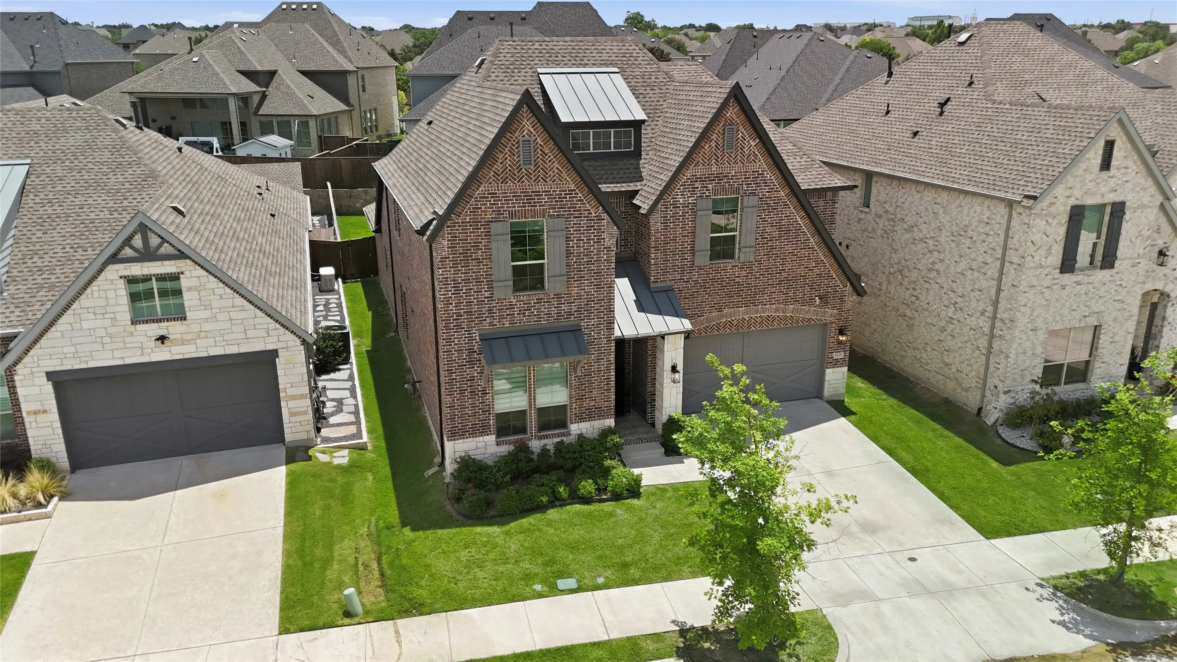 Brick and stone facade home featuring a two-car garage, covered entry, gabled rooflines, and mature landscaping