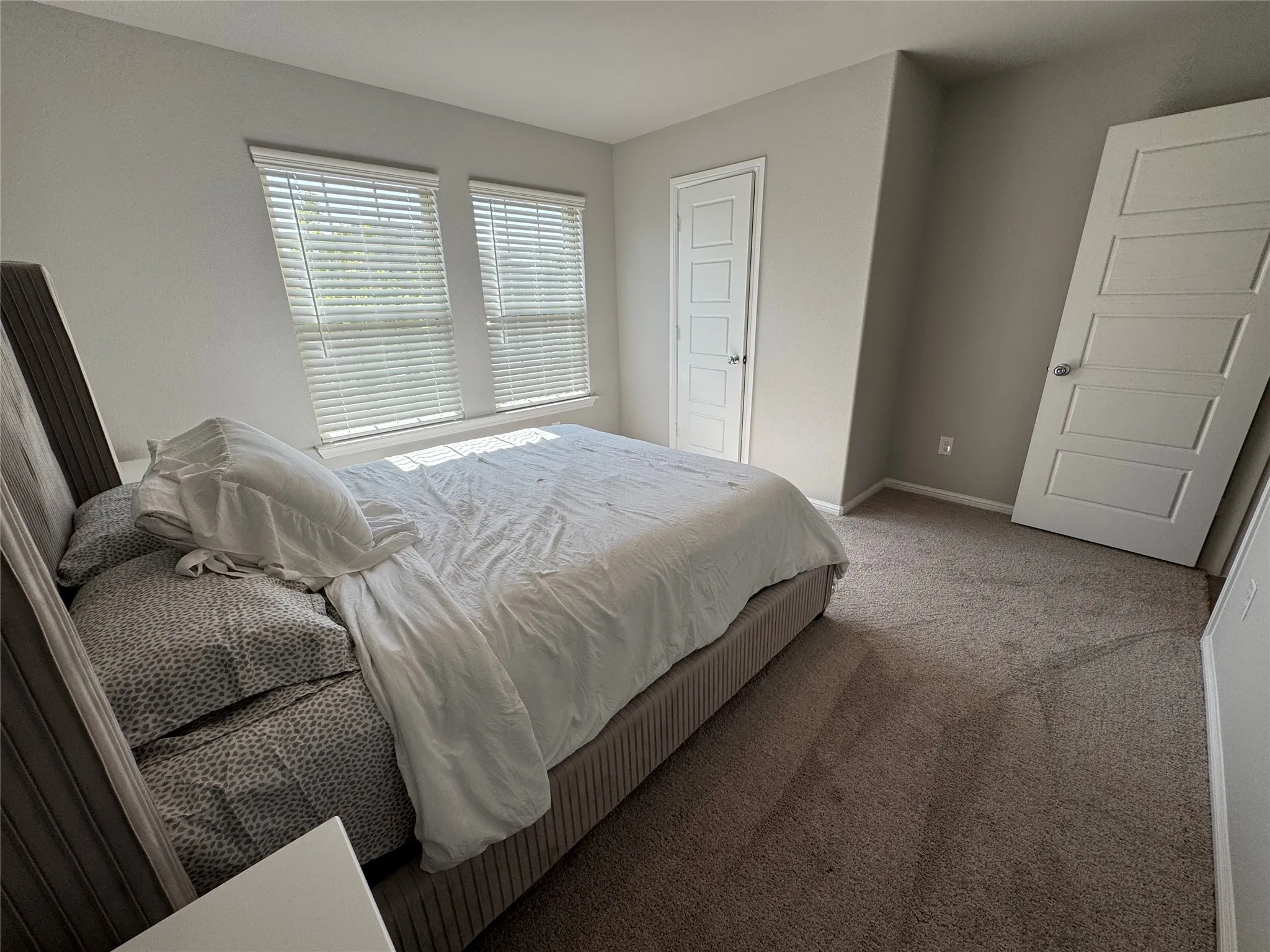 Carpeted room with two windows featuring horizontal blinds