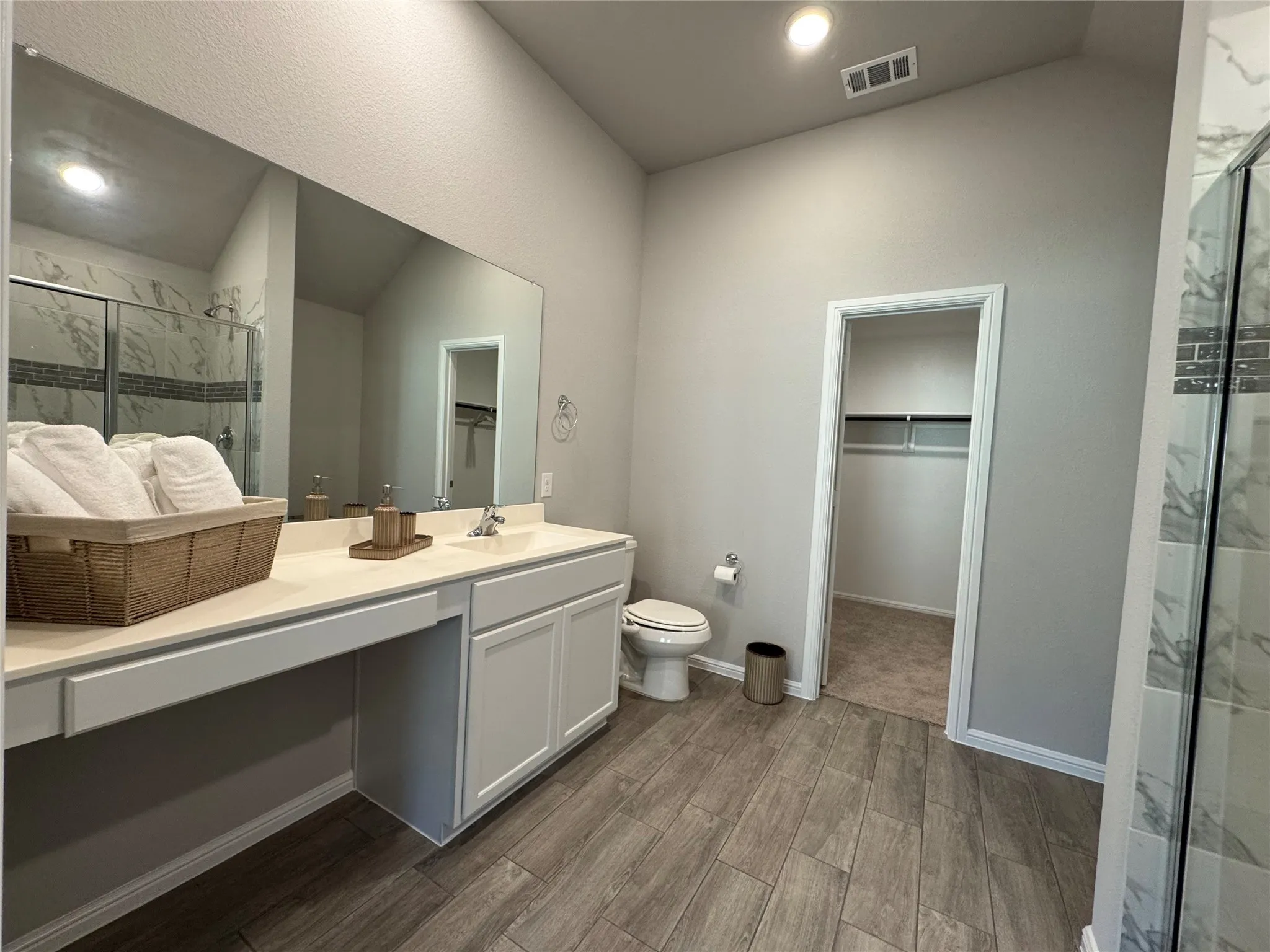 Bathroom featuring a double vanity with ample counter space, a separate toilet area, and wood-finish flooring