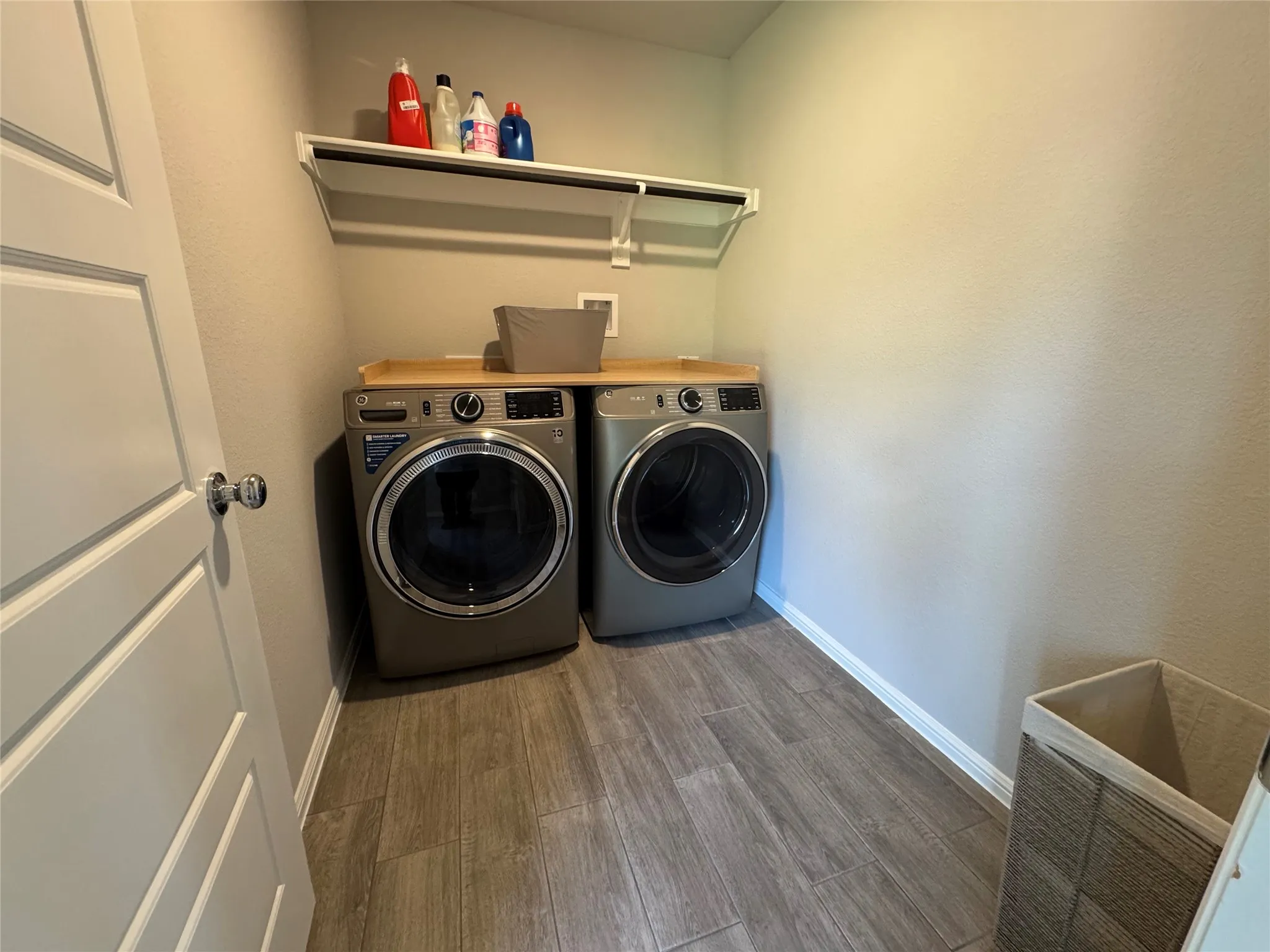 Dedicated laundry space featuring wood-finish tile flooring, a built-in shelf, and a hanging rod