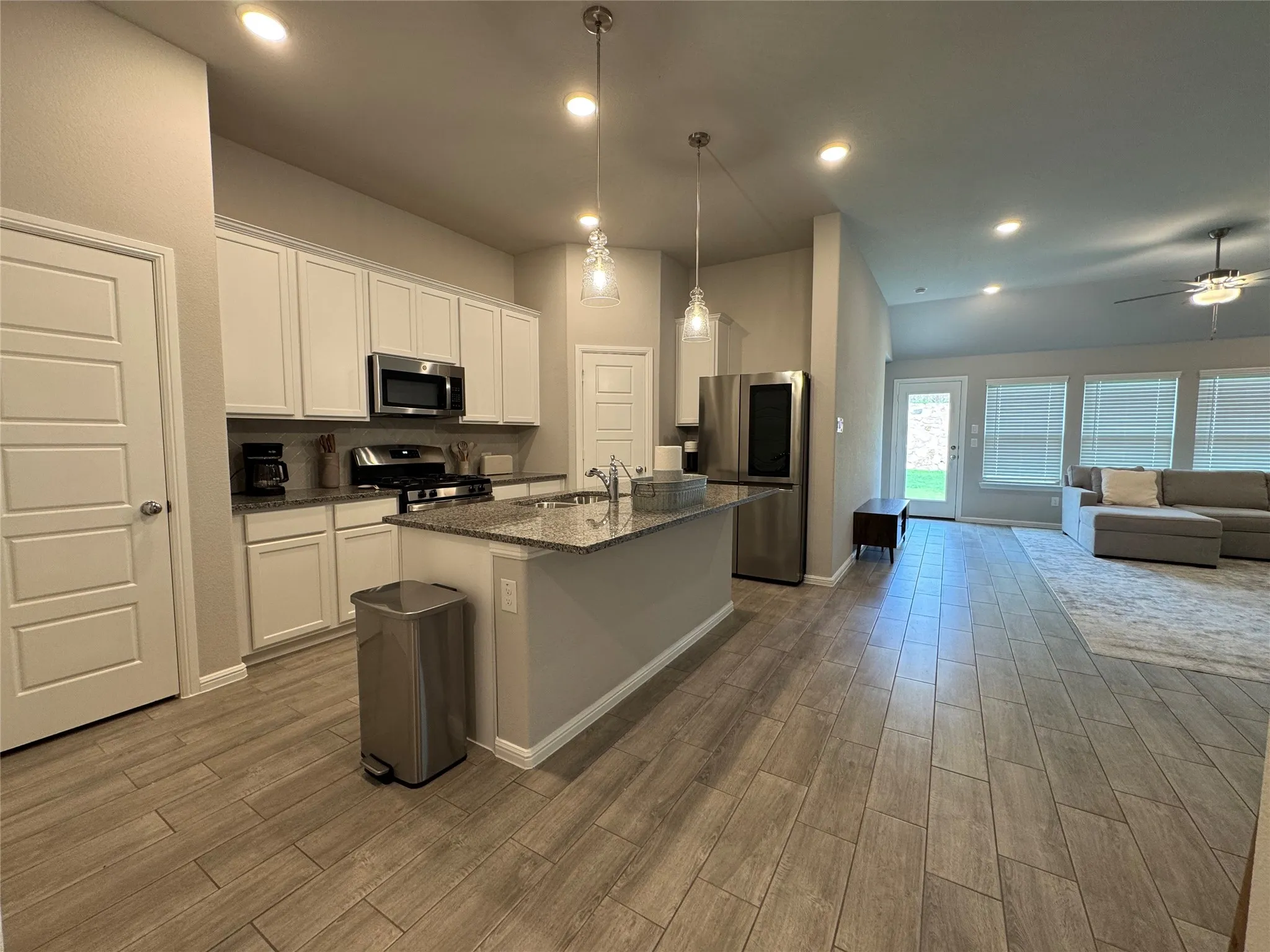 Kitchen featuring an island with a breakfast bar, stainless steel appliances, white cabinetry, and granite countertops