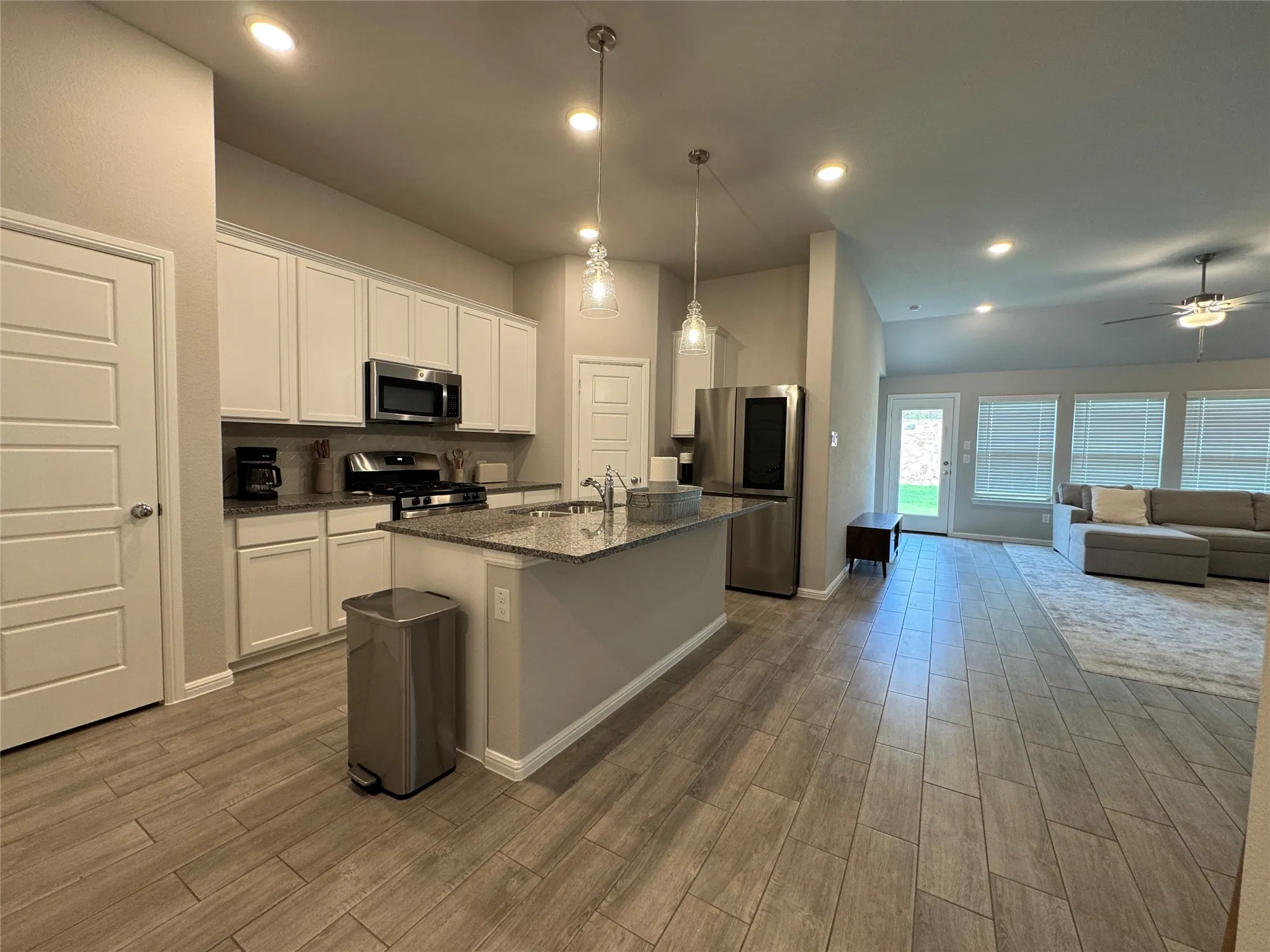 Open-concept kitchen and living area featuring wood-finish tile flooring