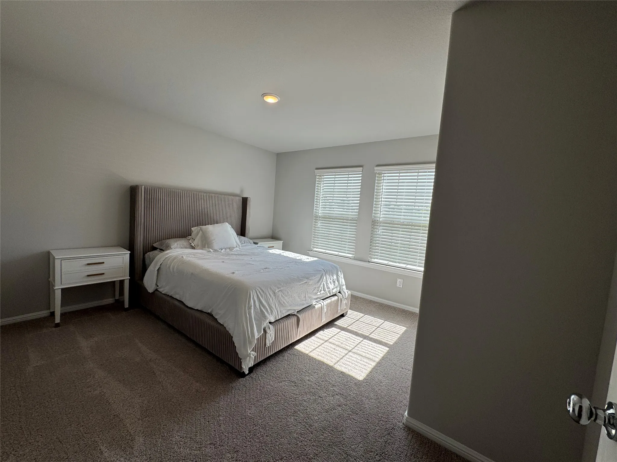 Carpeted room with a recessed ceiling light and two windows featuring horizontal blinds