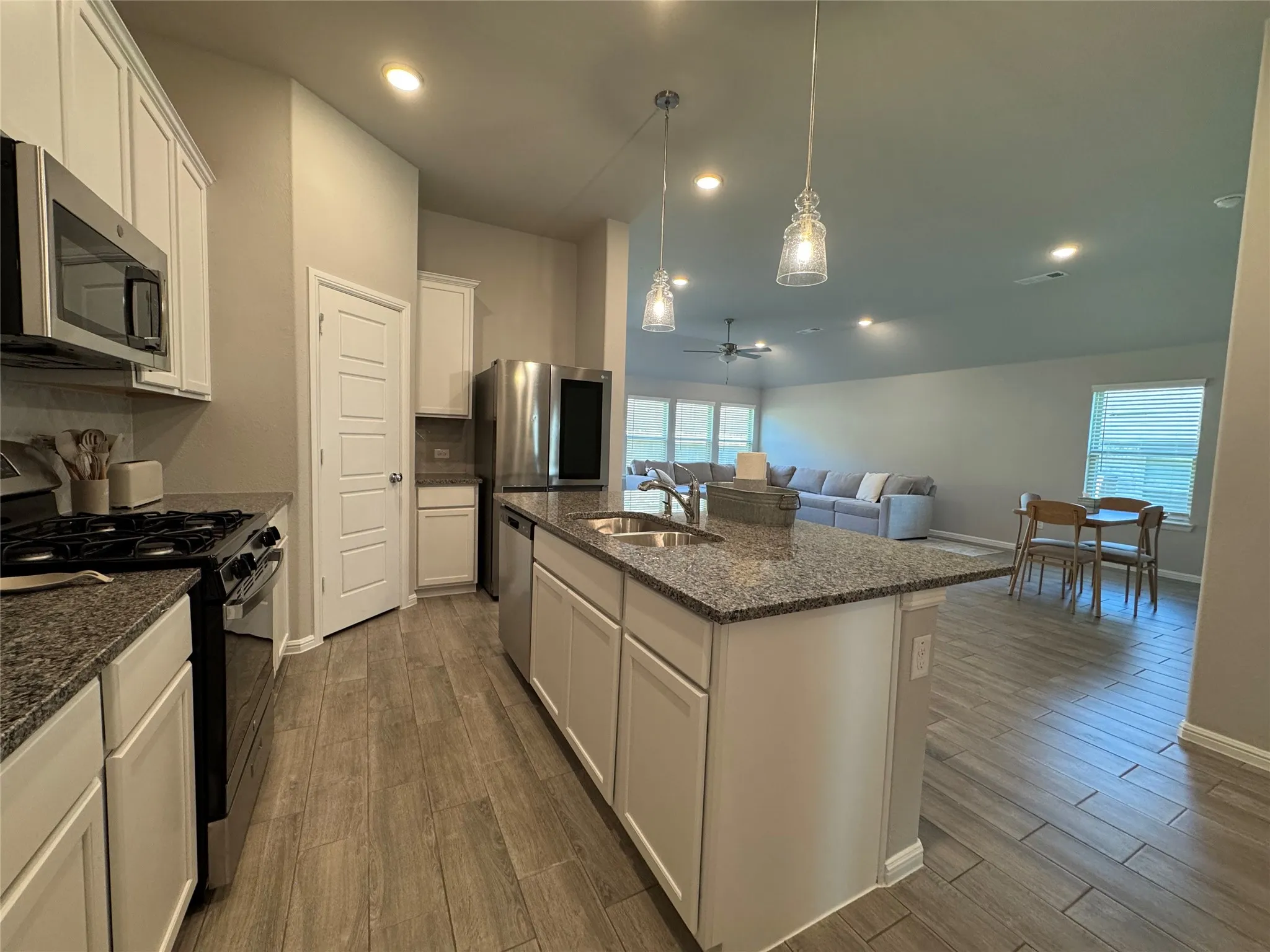 Kitchen island featuring a double-basin stainless steel sink, granite countertop, and white cabinetry