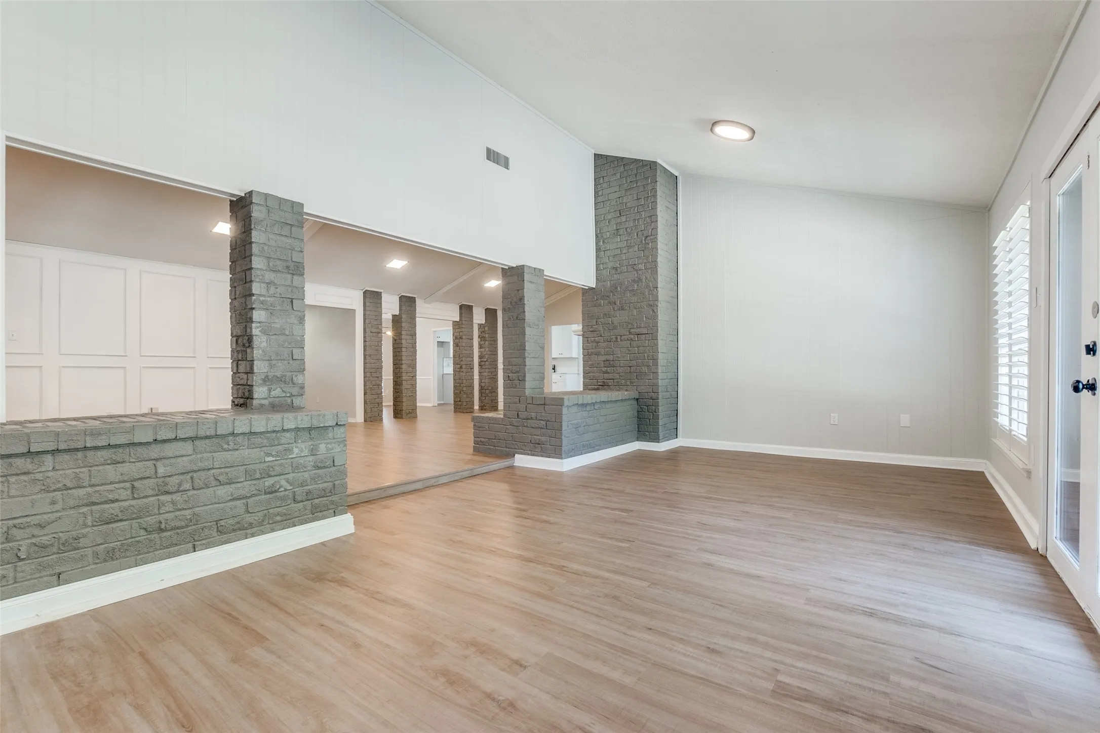 Spacious interior featuring wood-finish flooring, vaulted ceilings, and white paneled walls