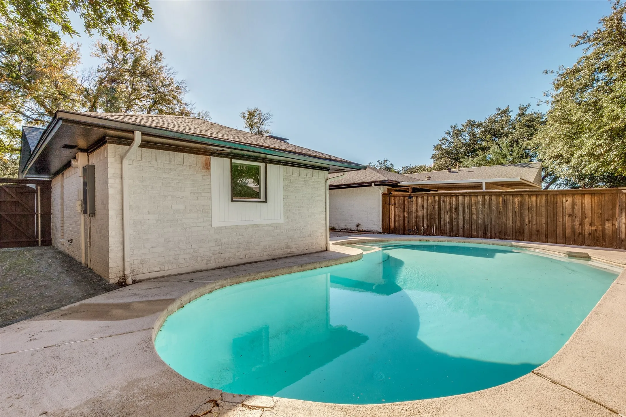 Curved swimming pool featuring a light-colored patio surround