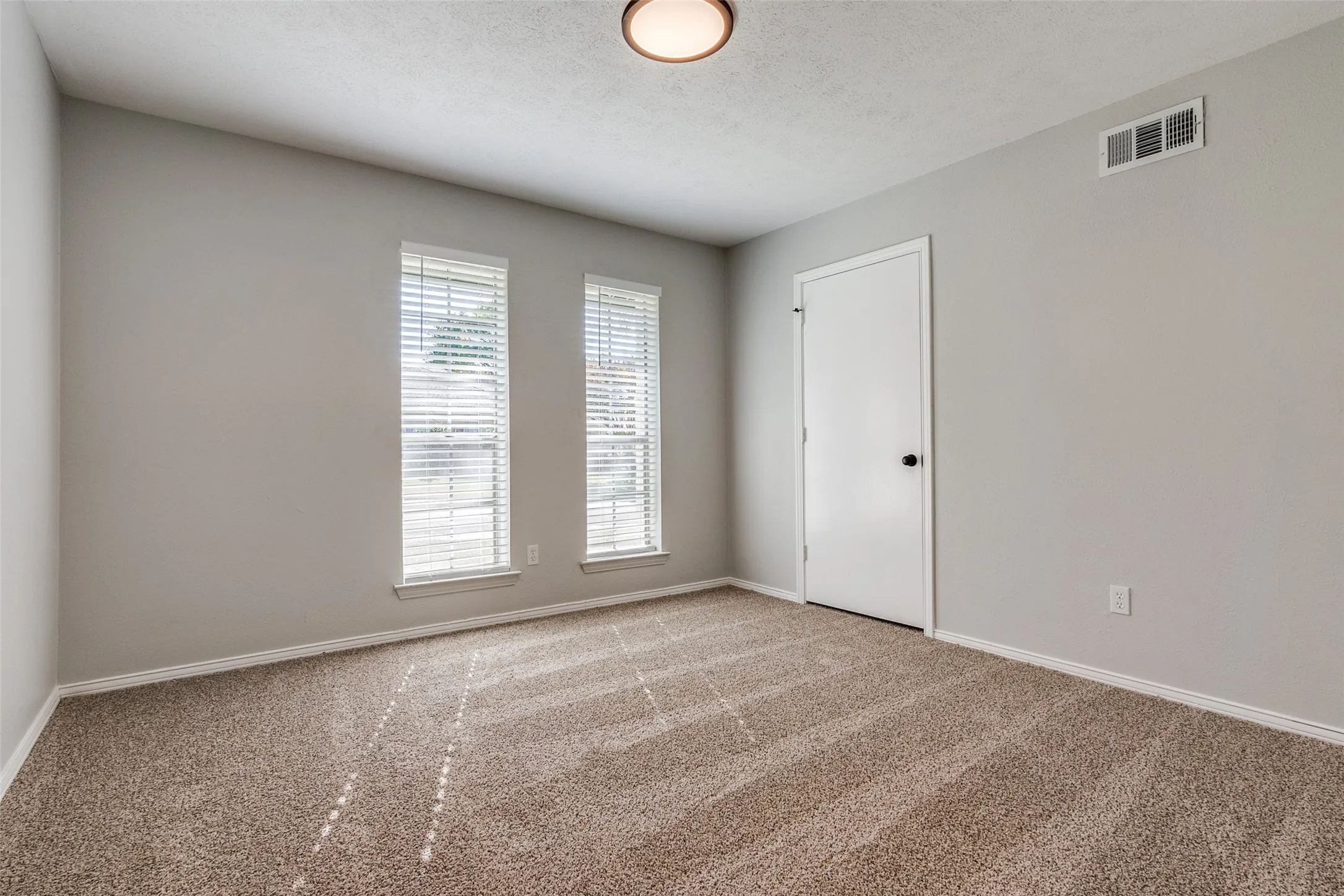 Room featuring light gray walls, neutral carpet flooring, and white trim