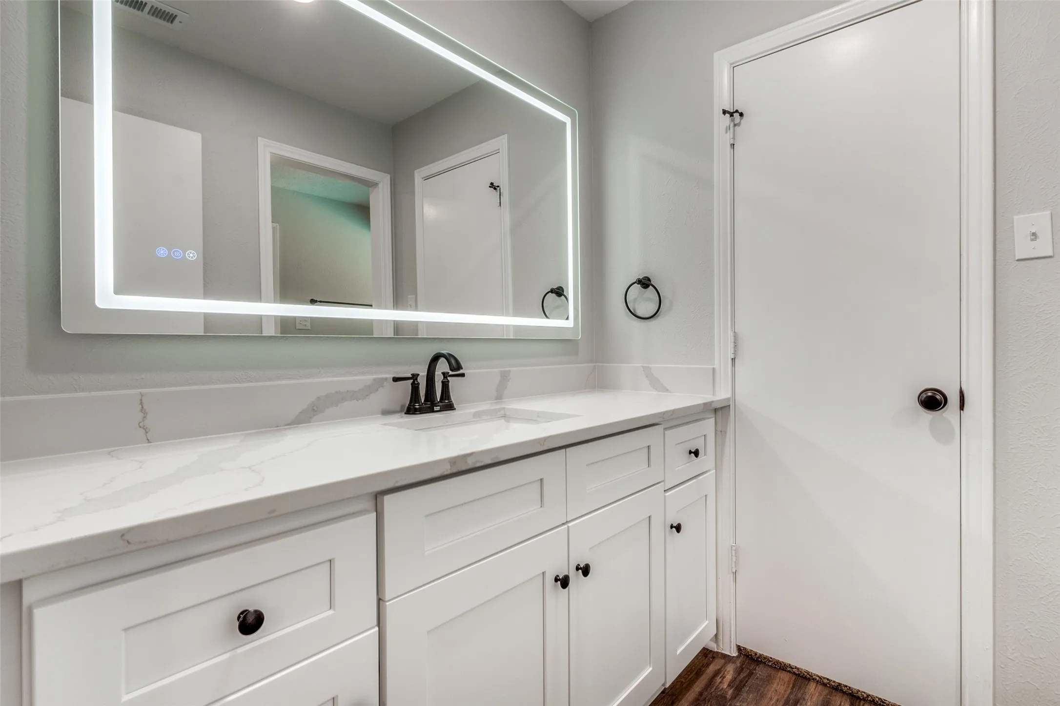 Bathroom vanity featuring a quartz countertop, integrated sink, and matte black faucet