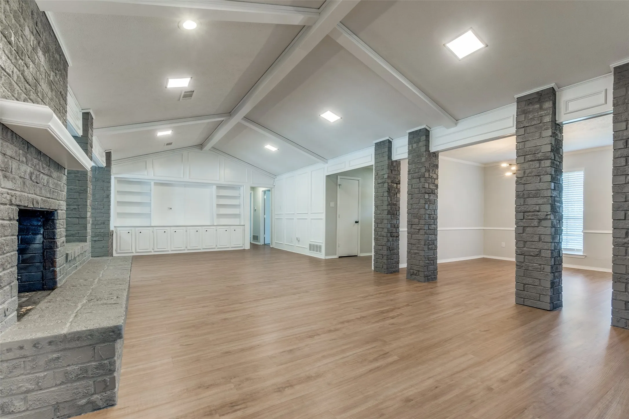 Spacious interior featuring wood-finish flooring, vaulted ceilings with exposed beams, and recessed lighting