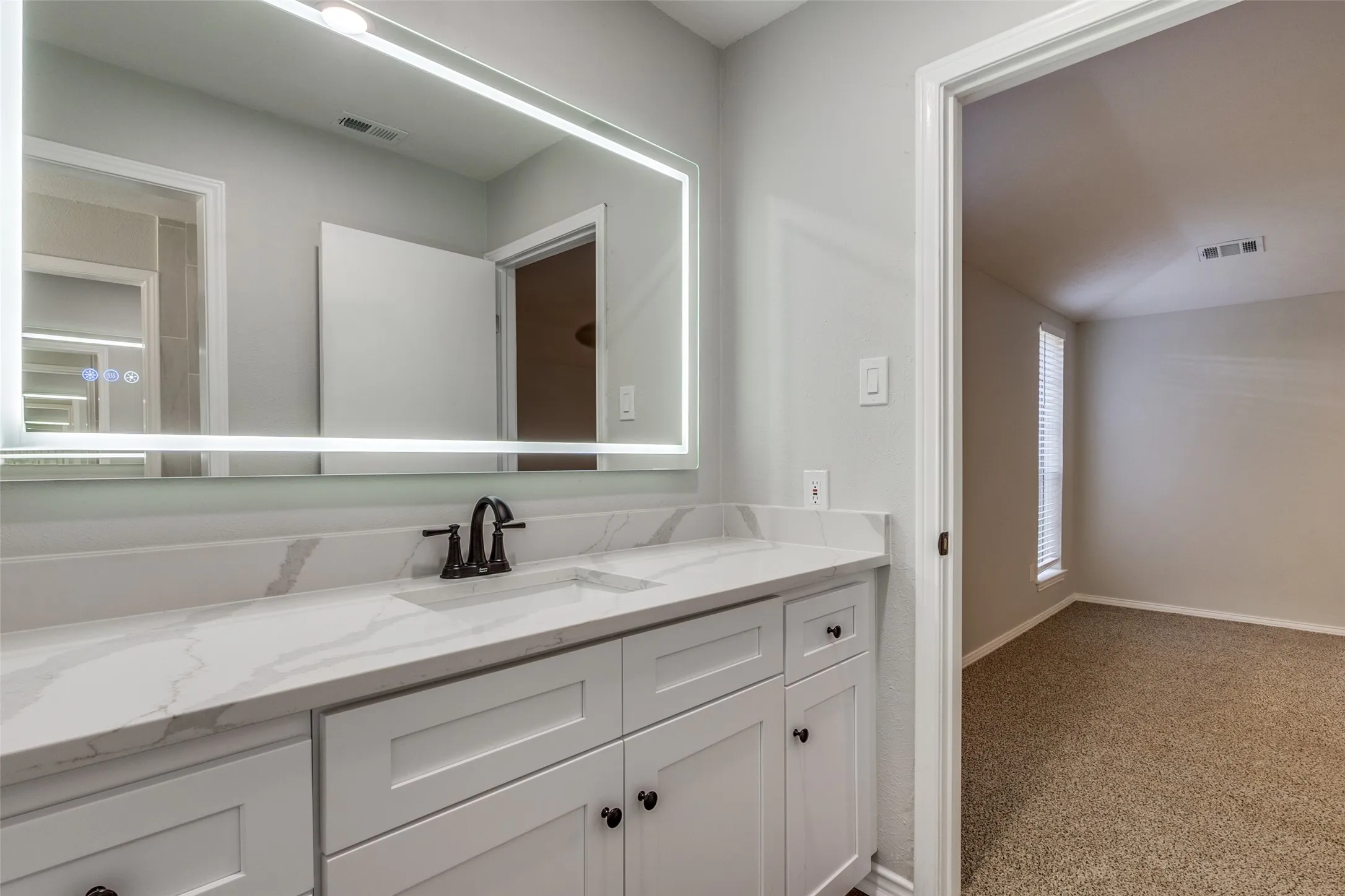 Modern vanity featuring white shaker-style cabinetry, a single basin sink, and a black faucet