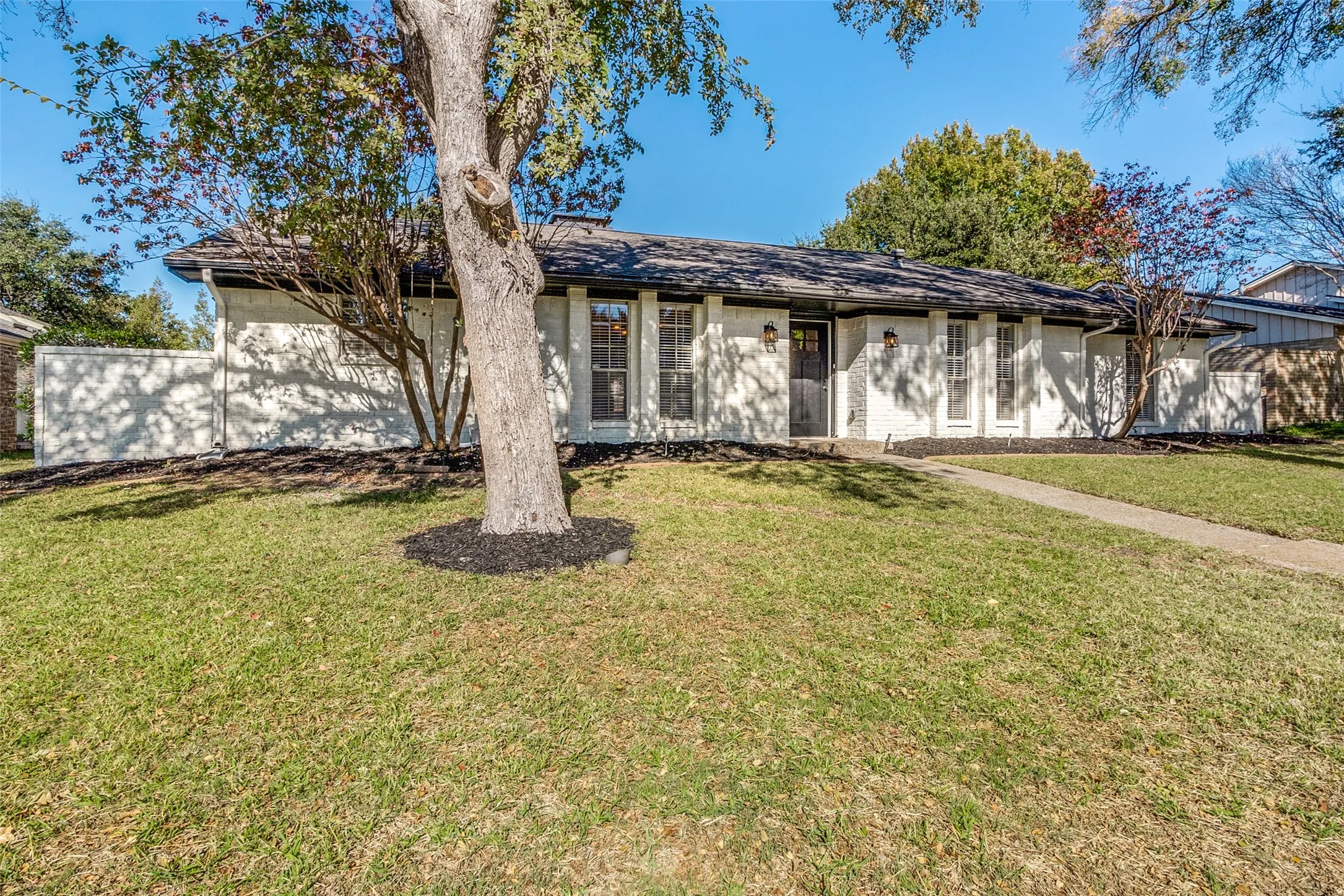 Single-story residence featuring a dark roof, white exterior siding, and dark trim