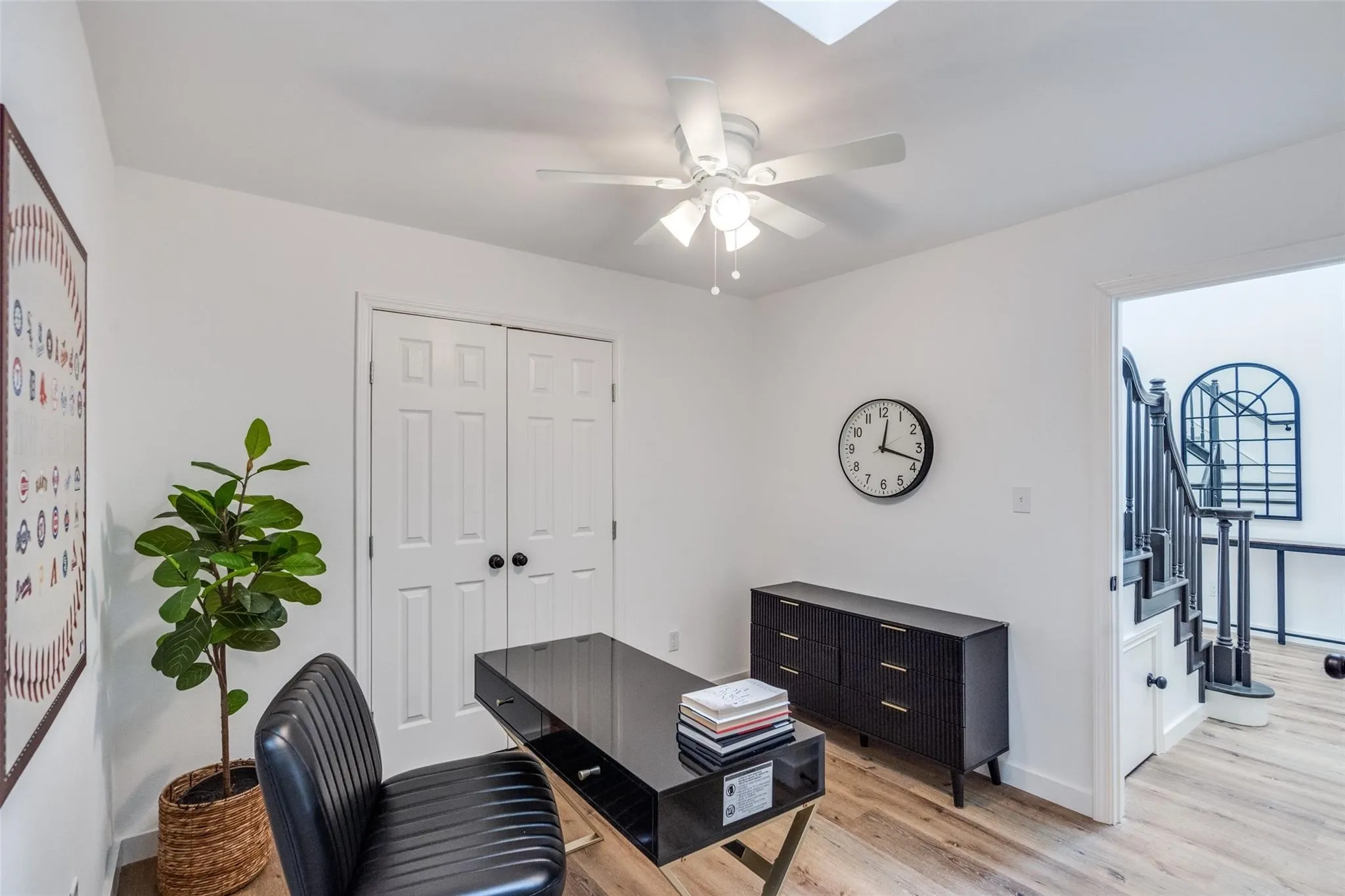 Bright room featuring wood-finish flooring, a ceiling fan, and white double doors