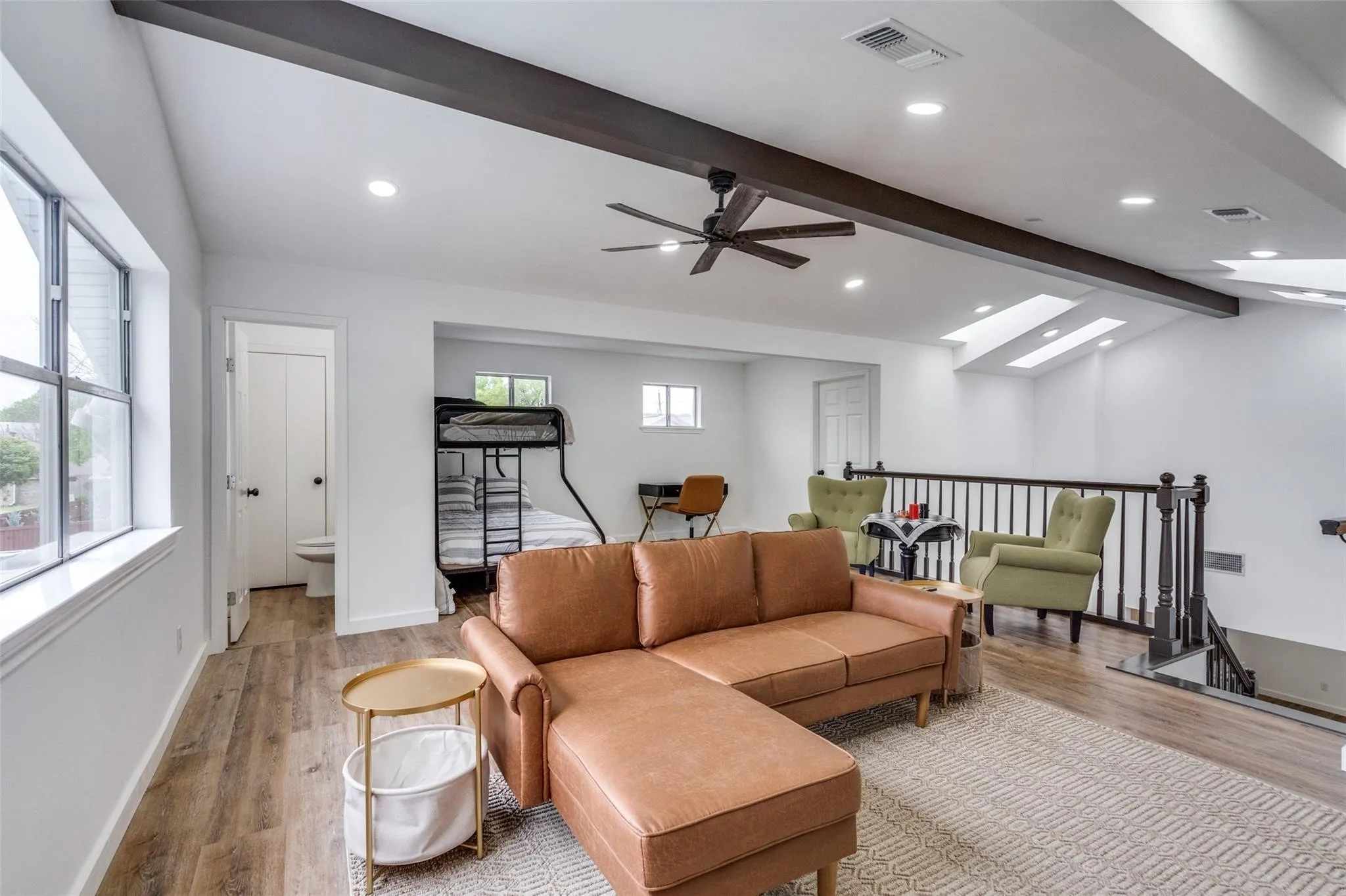 Open-concept living area featuring wood-finish flooring, recessed lighting, and exposed ceiling beams