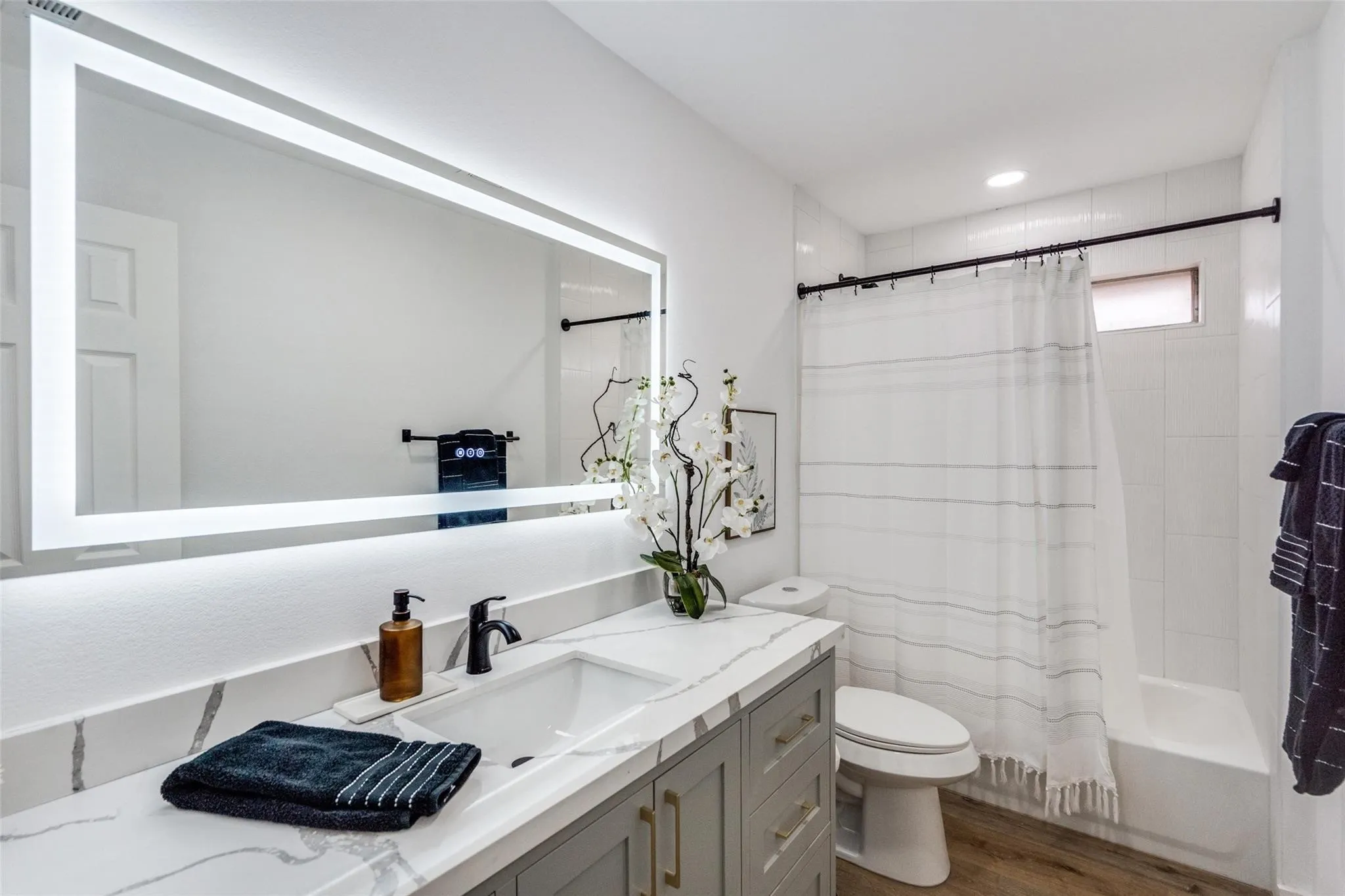 Bathroom featuring a floating vanity with a single basin sink, a quartz-finish countertop, and matte black fixtures