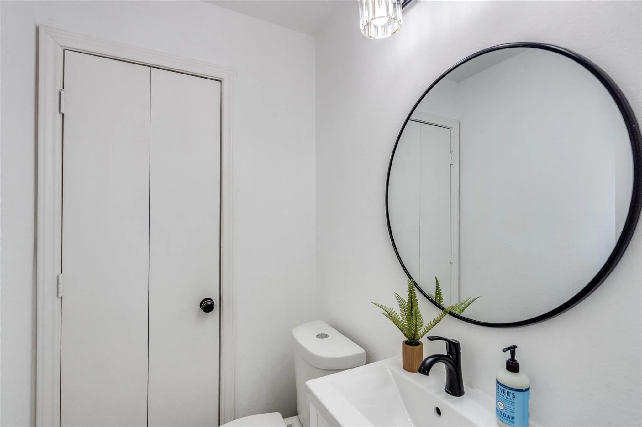 Vanity with an integrated rectangular sink, matte black faucet, and a round black-framed mirror