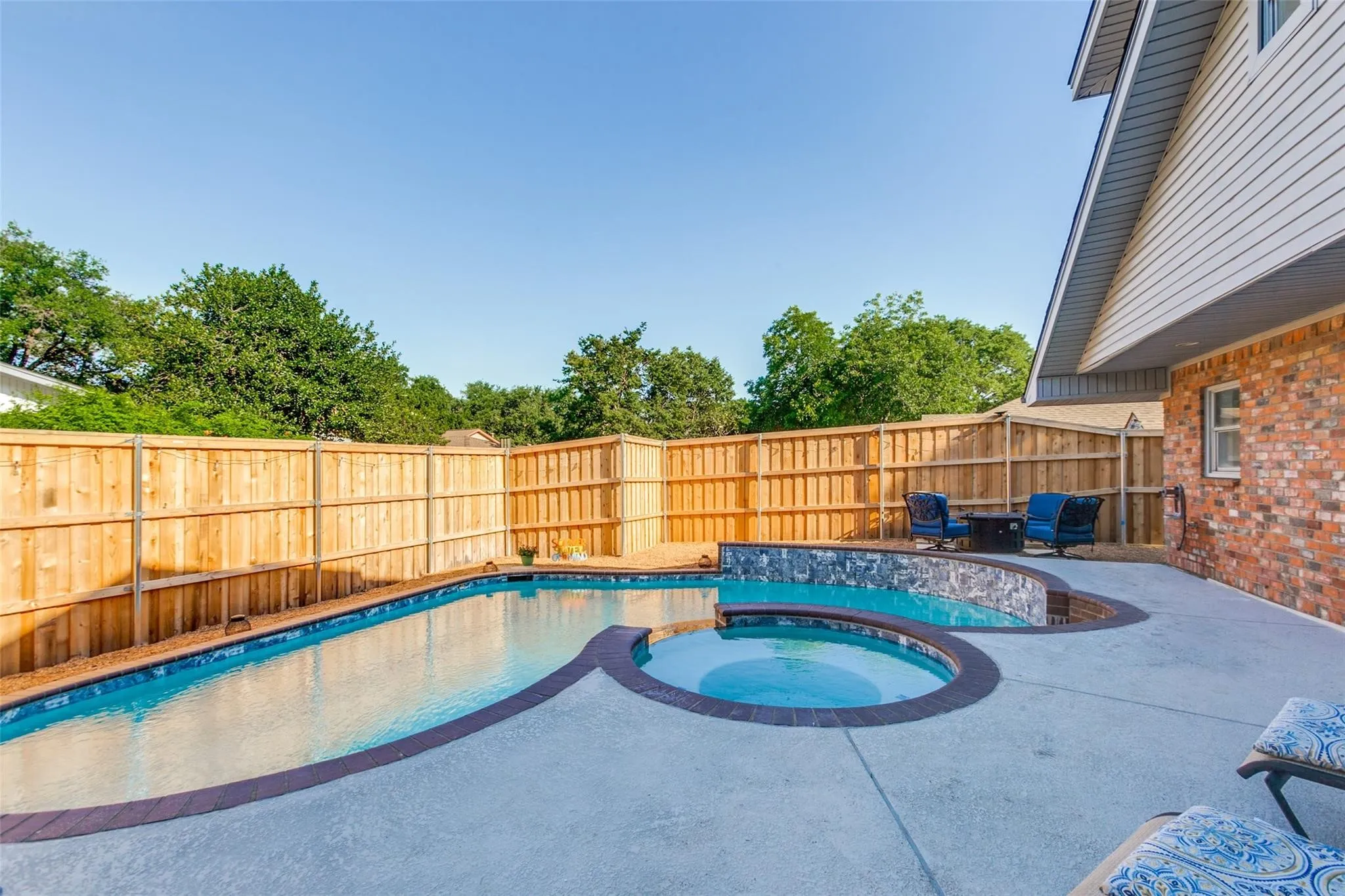 Private backyard oasis featuring a custom-shaped swimming pool with an integrated spa