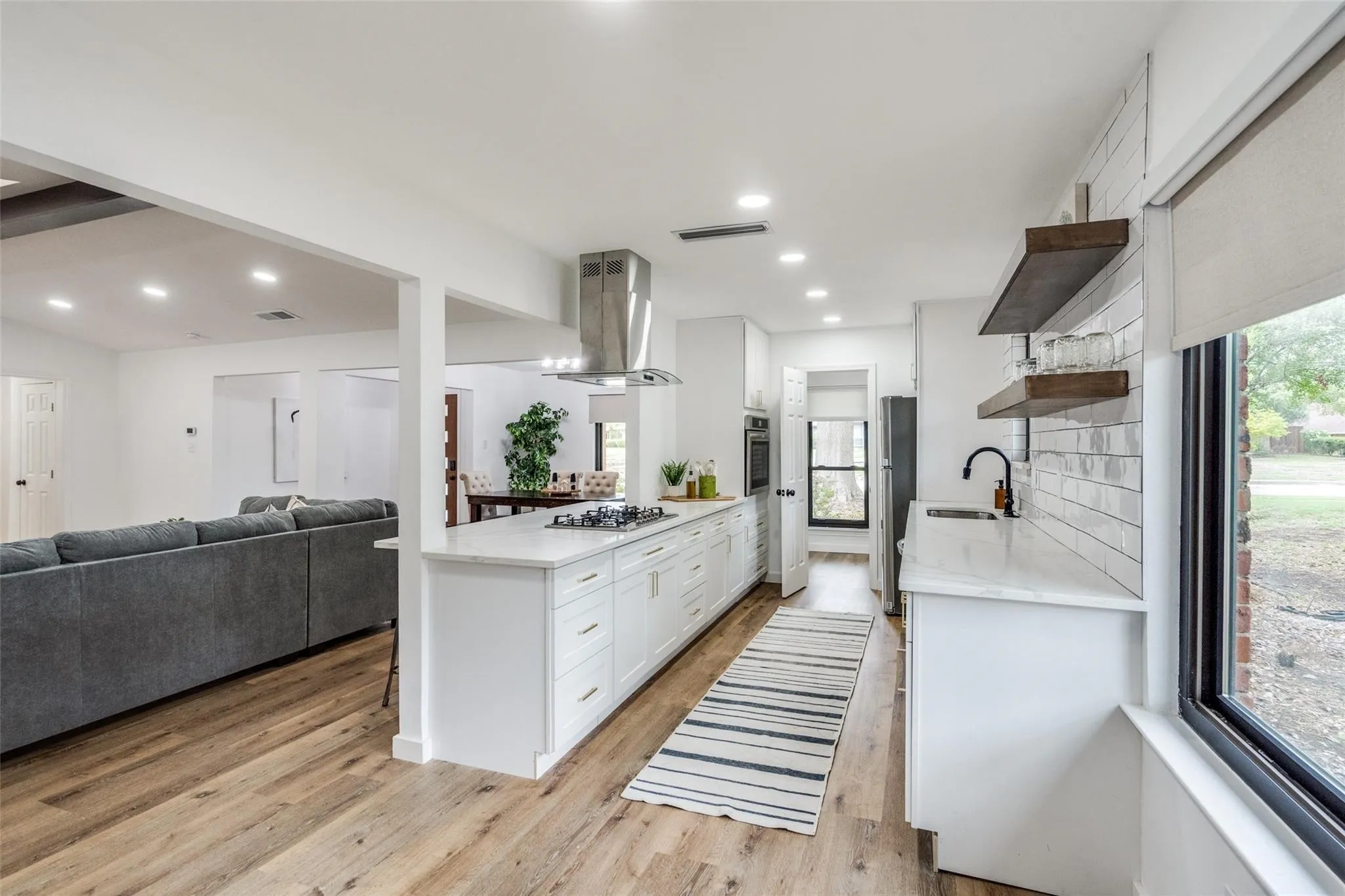 Expansive kitchen featuring a large central island with an integrated cooktop and stainless steel vent hood