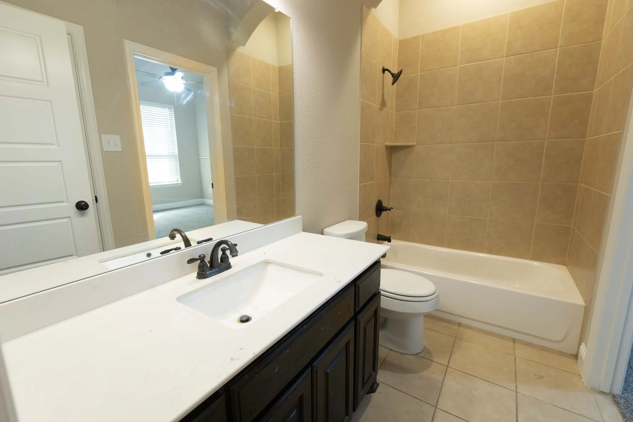 1st floor Bathroom featuring a dark wood-finish vanity with an integrated sink, white countertop, and a bronze-finish faucet