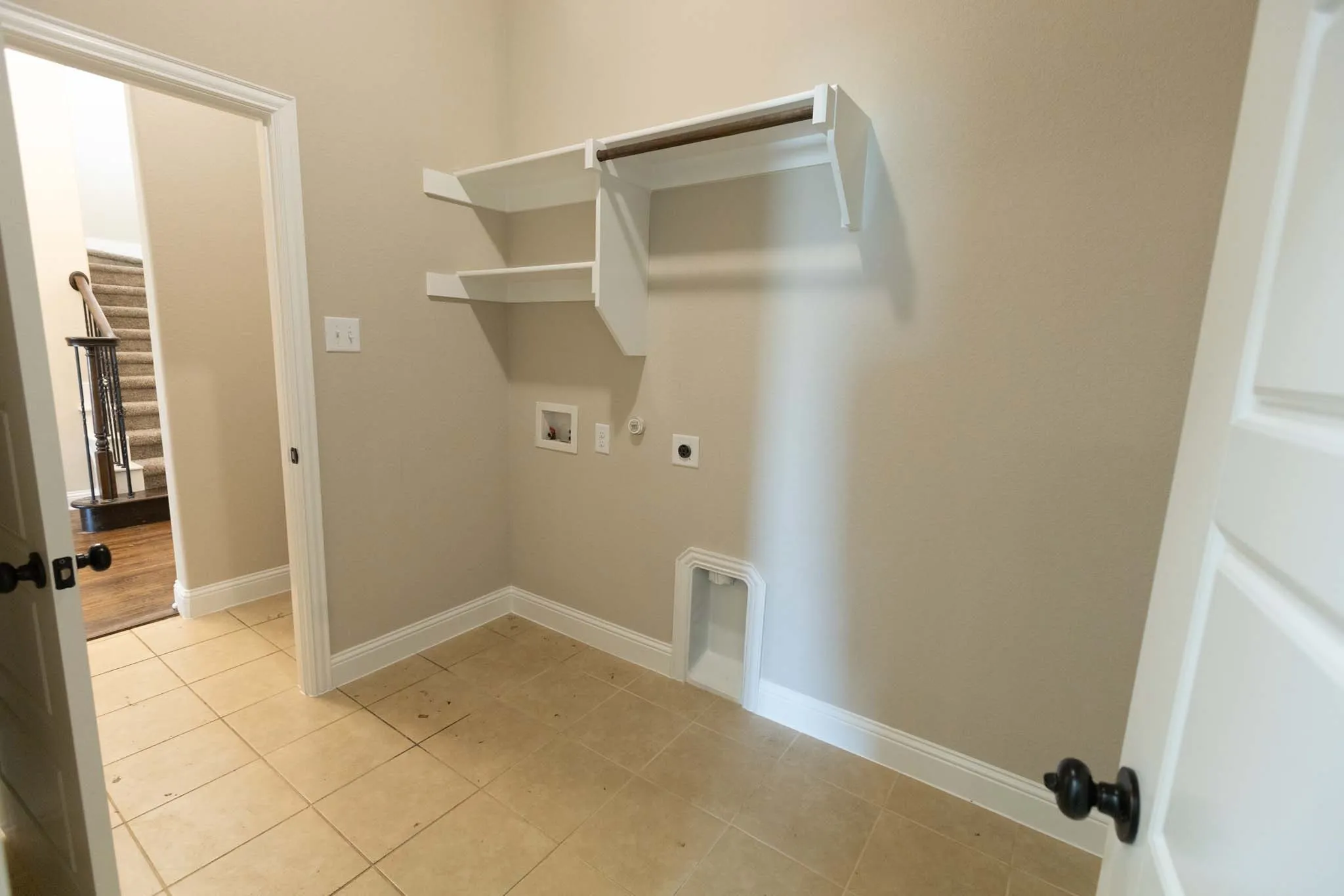 Laundry area featuring tile flooring, built-in shelving, and a hanging rod