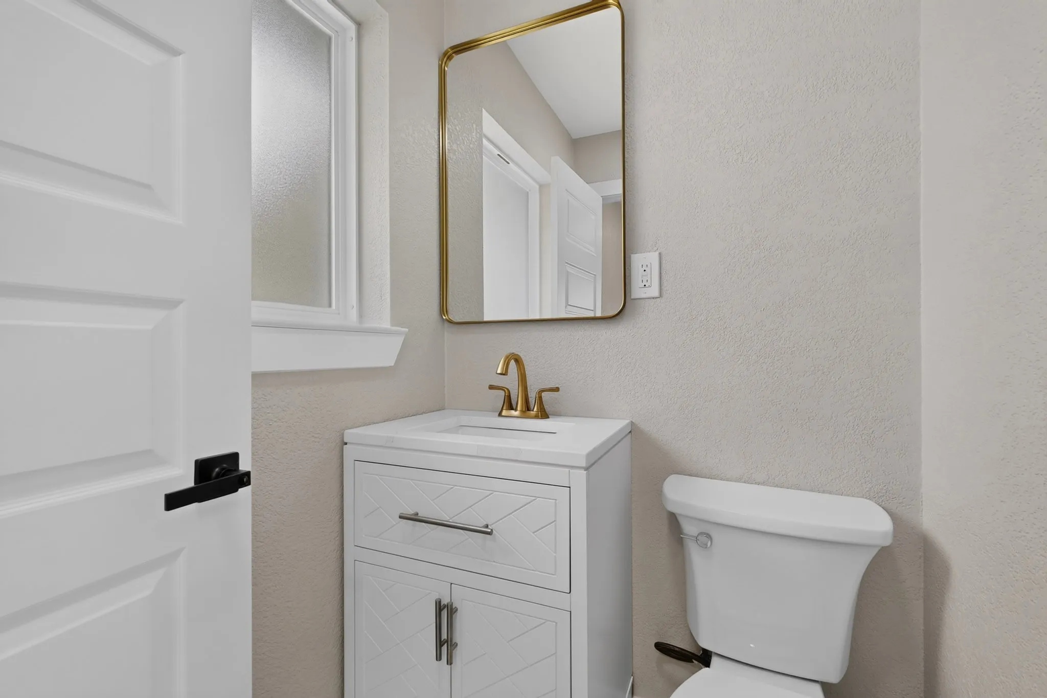 Bathroom vanity with a white countertop and gold-toned faucet