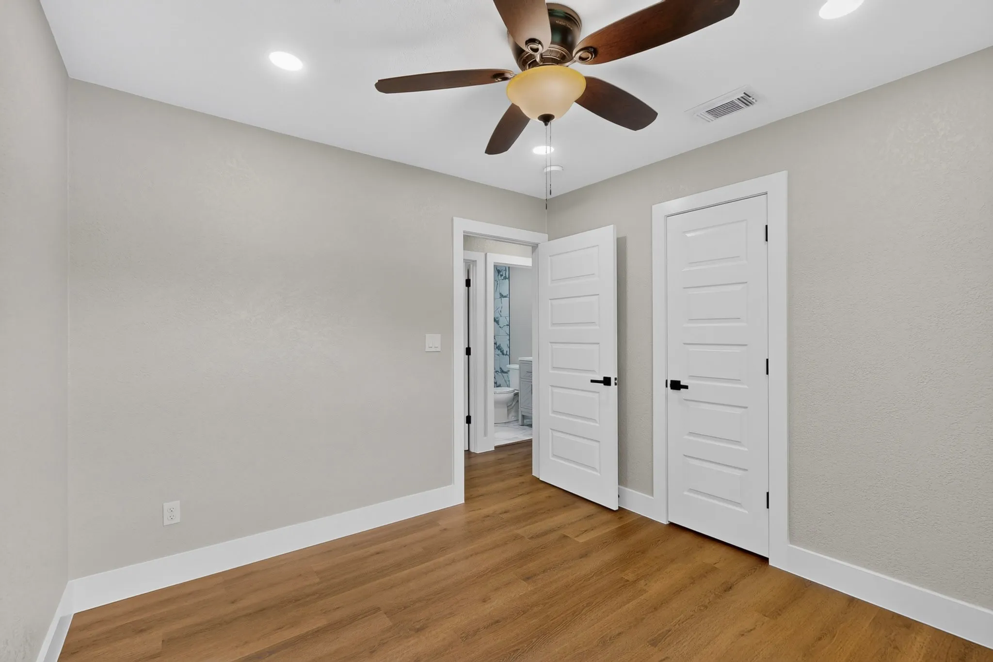 Interior room featuring wood-finish flooring, light gray walls, and white baseboards