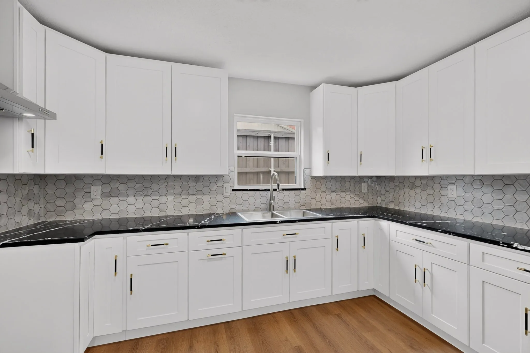 Spacious kitchen featuring white shaker-style cabinetry, black countertops, and a hexagon tile backsplash