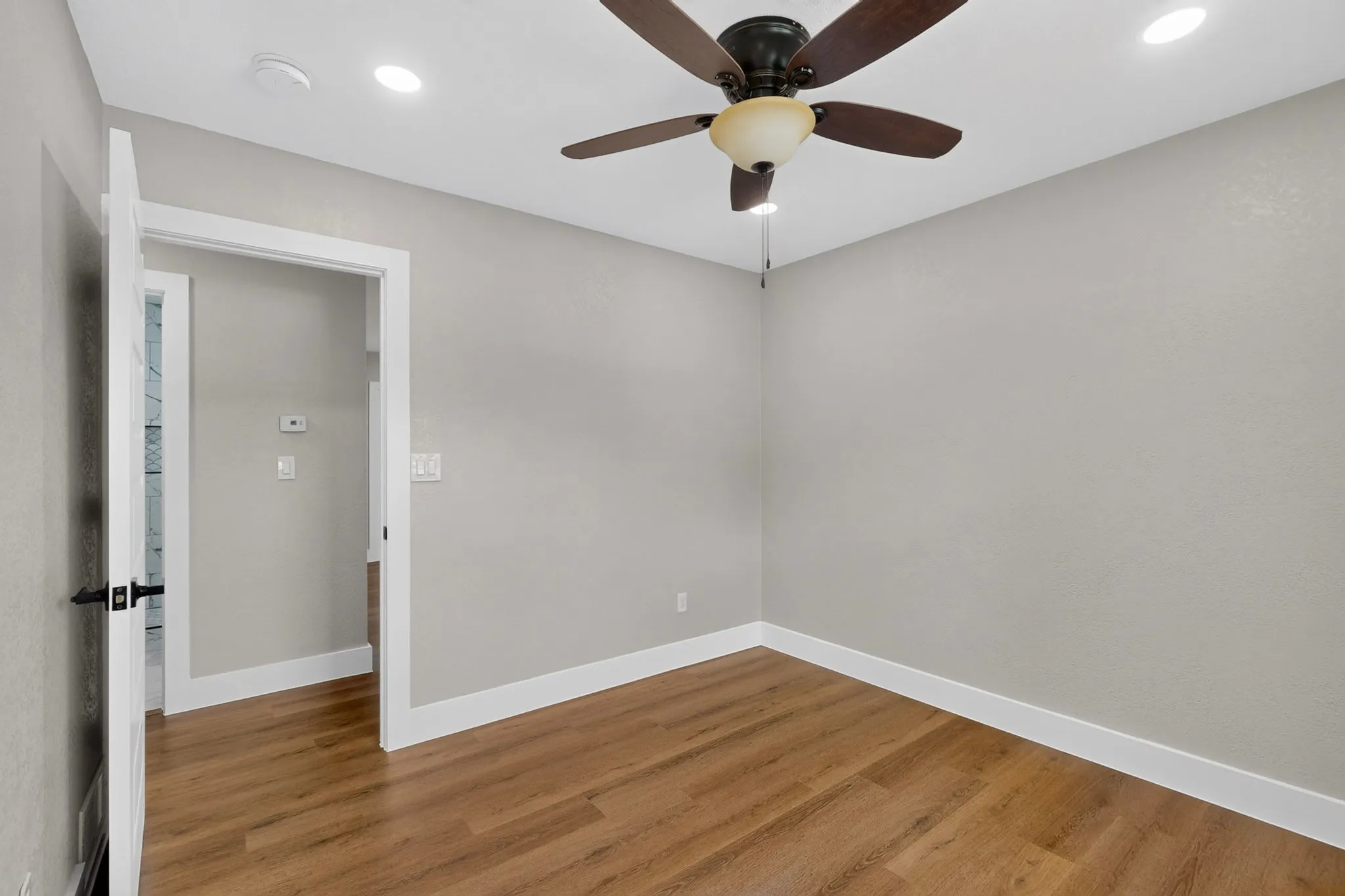 Warm wood-finish flooring with white baseboards