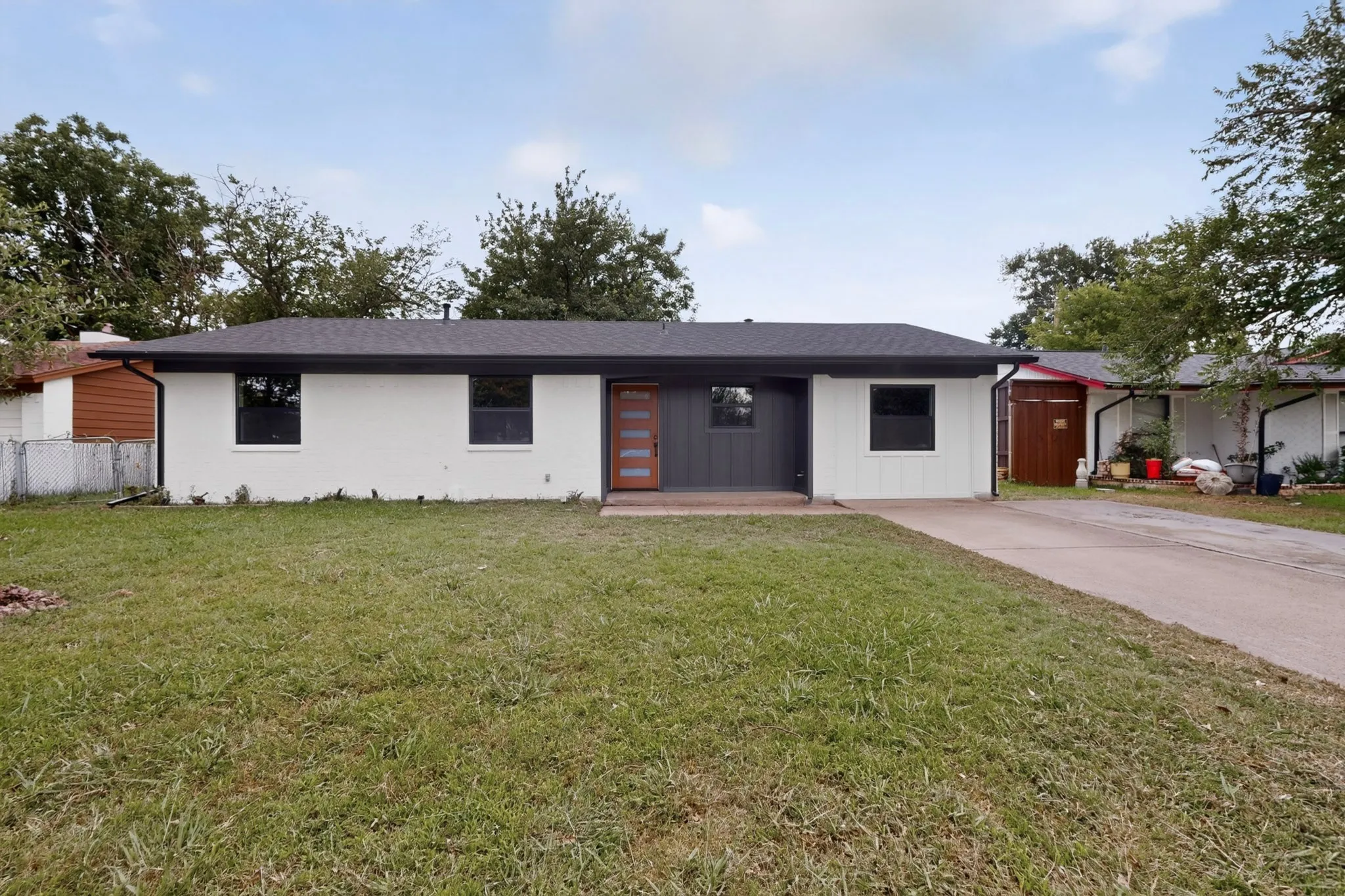 Contemporary ranch-style residence featuring a dark shingle roof and a contrasting black and white exterior