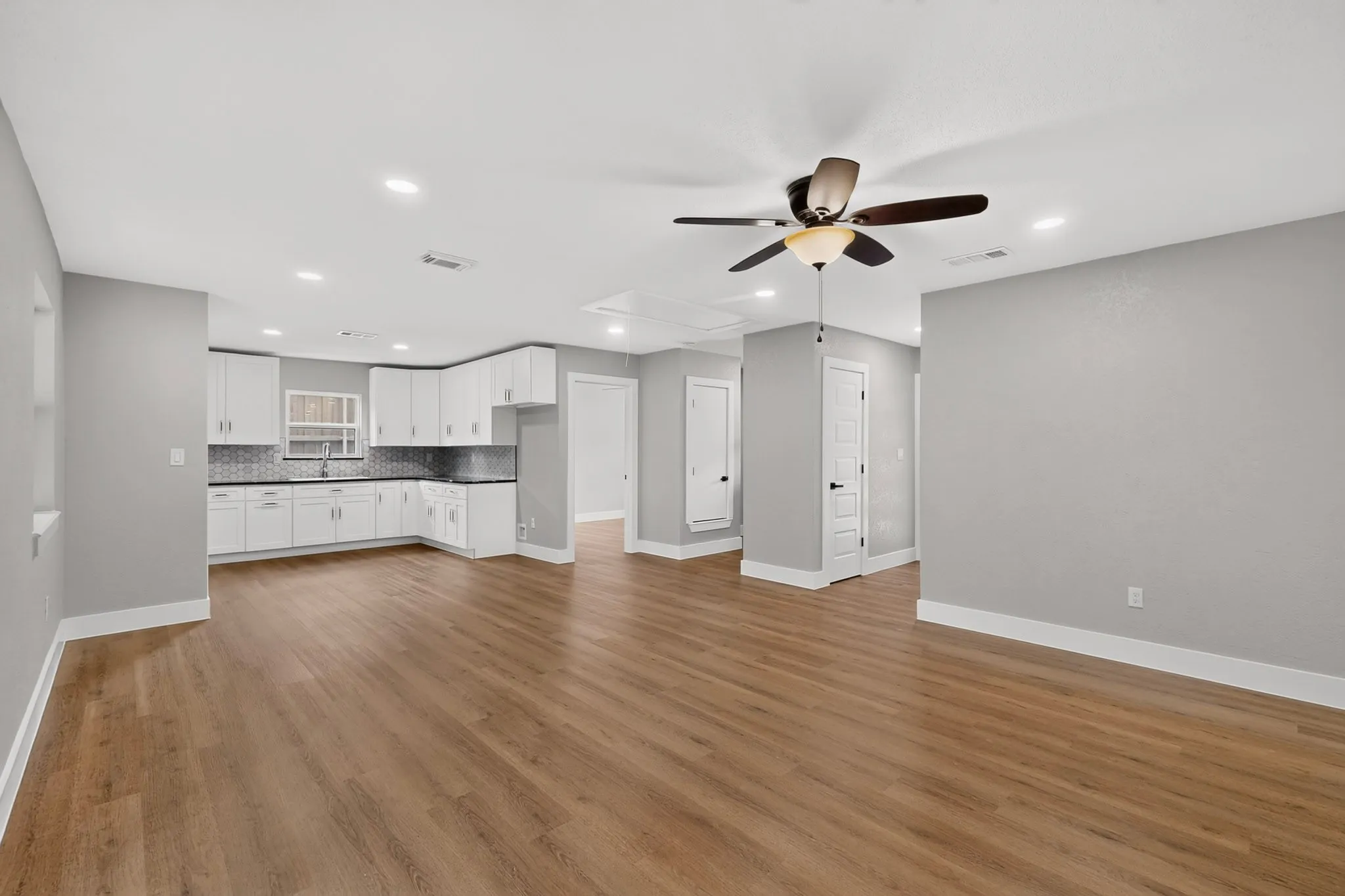Open-concept main living area with wood-finish flooring, recessed lighting, and a ceiling fan