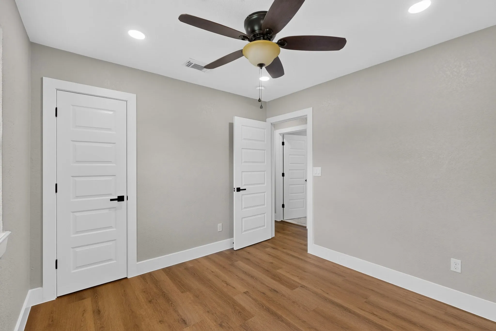 Spacious room featuring wood-finish flooring and neutral wall tones