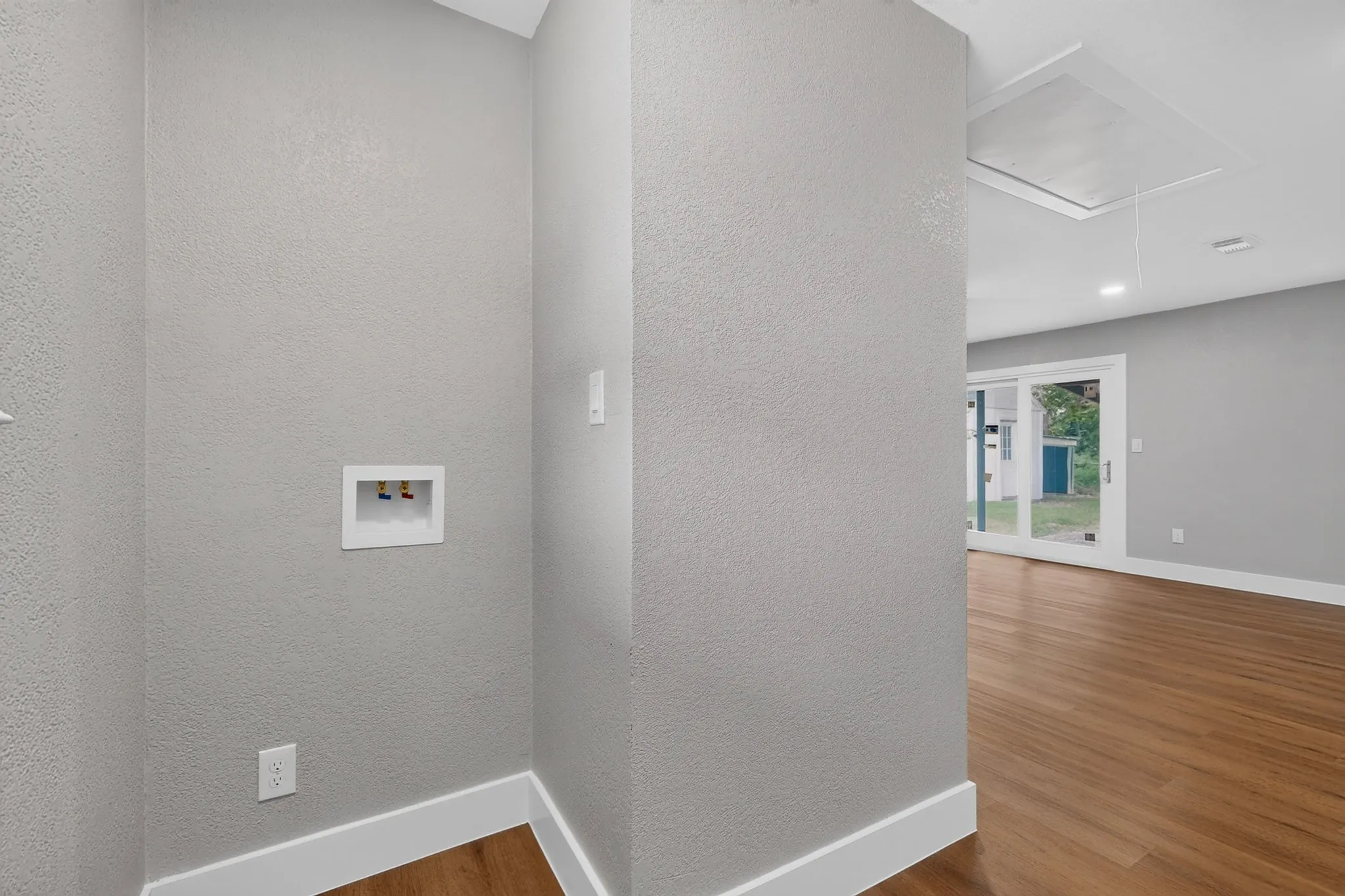 Dedicated utility area with connections, textured walls, and white baseboards