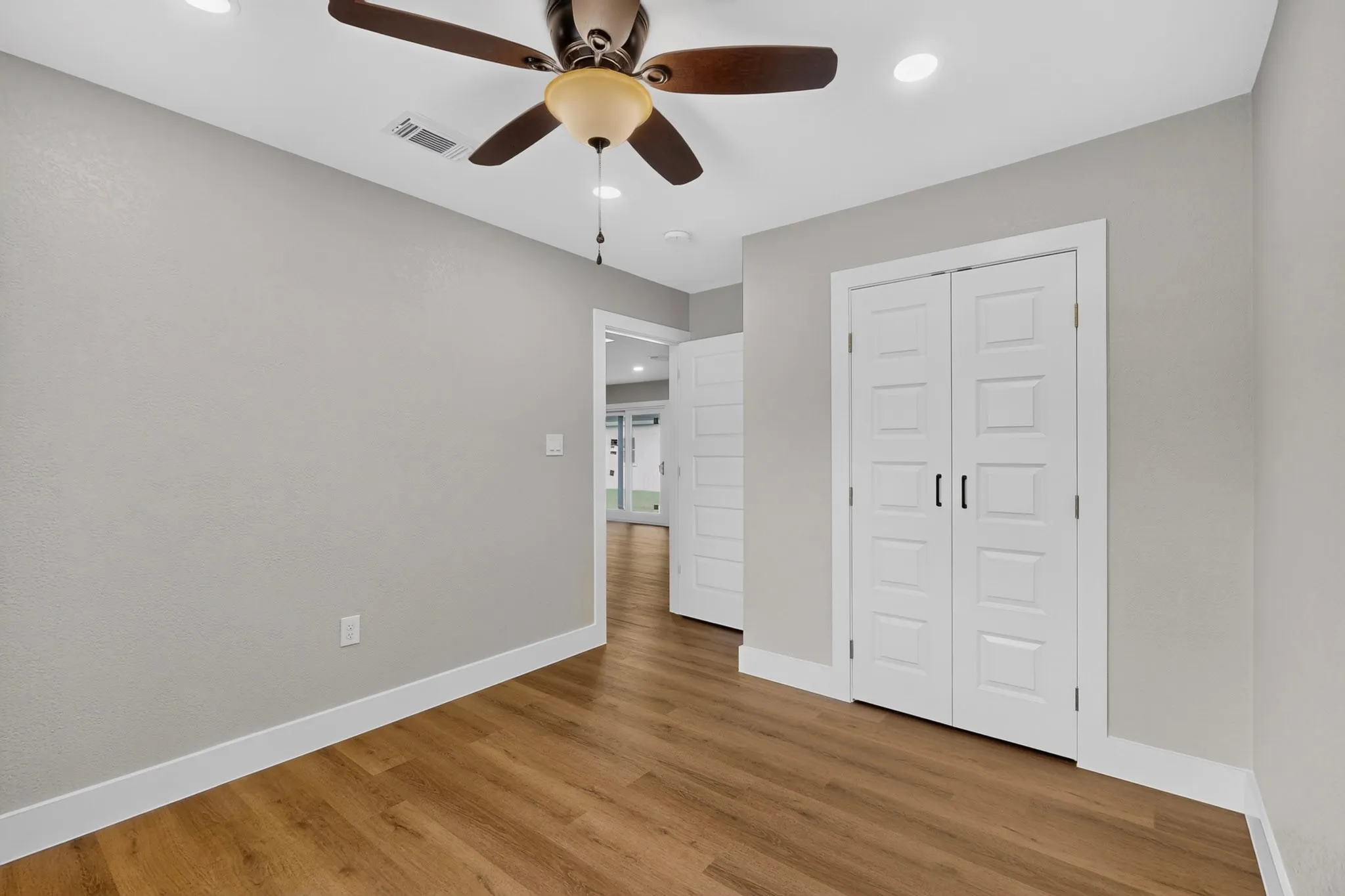 Interior room featuring wood-finish flooring, light gray walls, and white baseboards