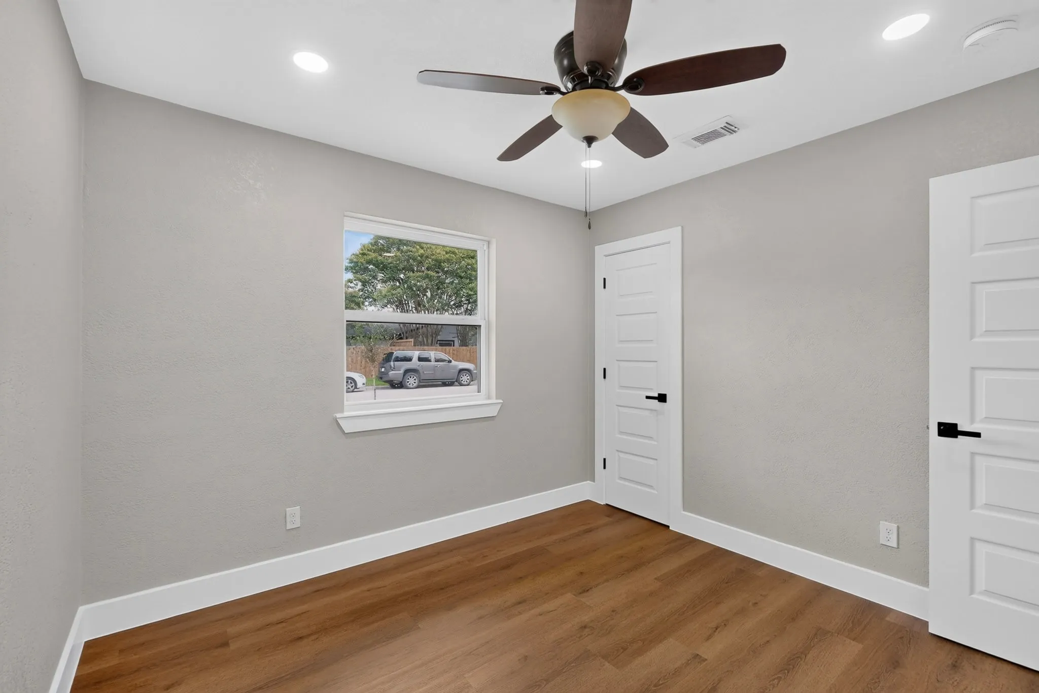 Room featuring wood-finish flooring, light grey walls, and white trim