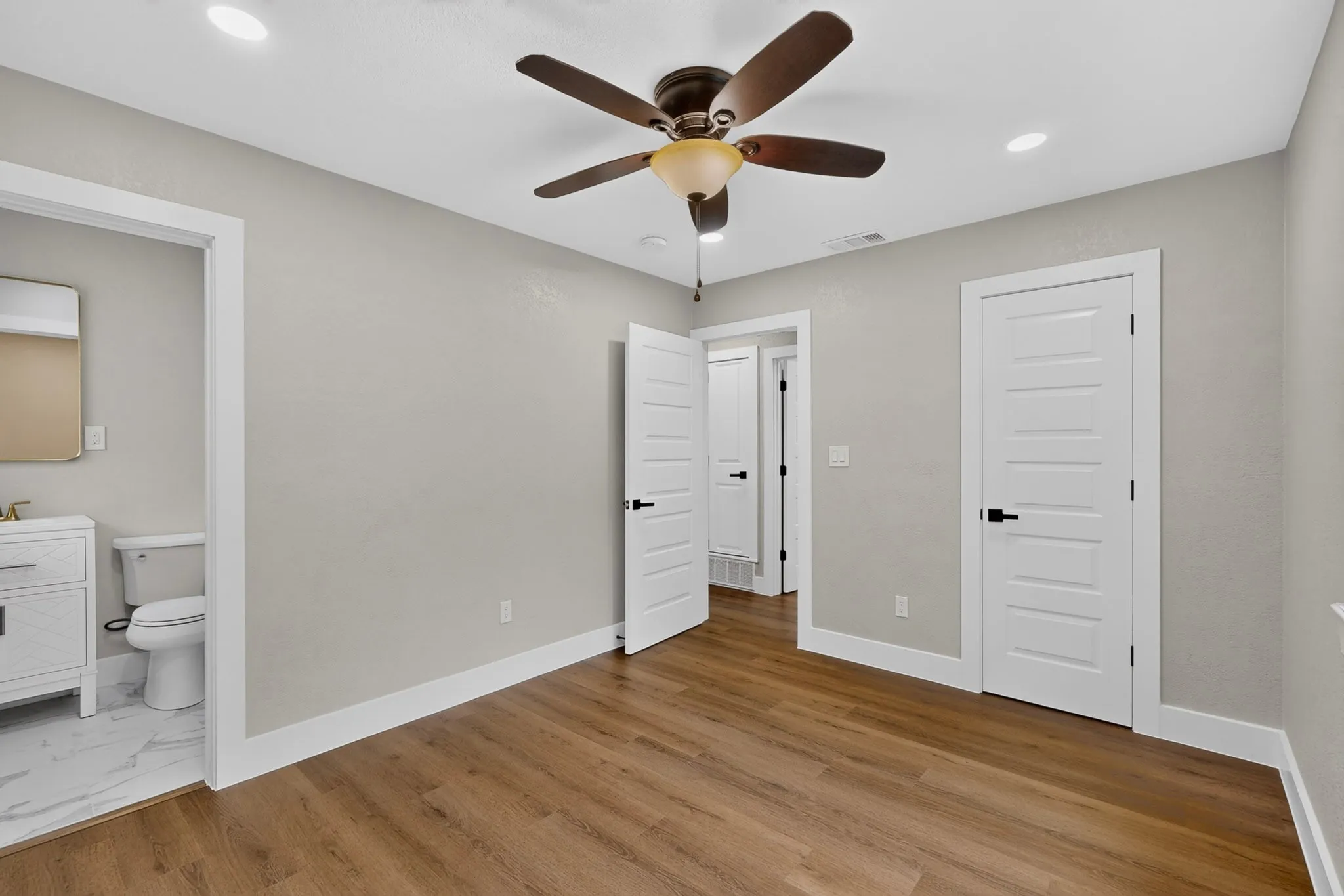 Spacious room featuring wood-finish flooring, recessed lighting, and a ceiling fan