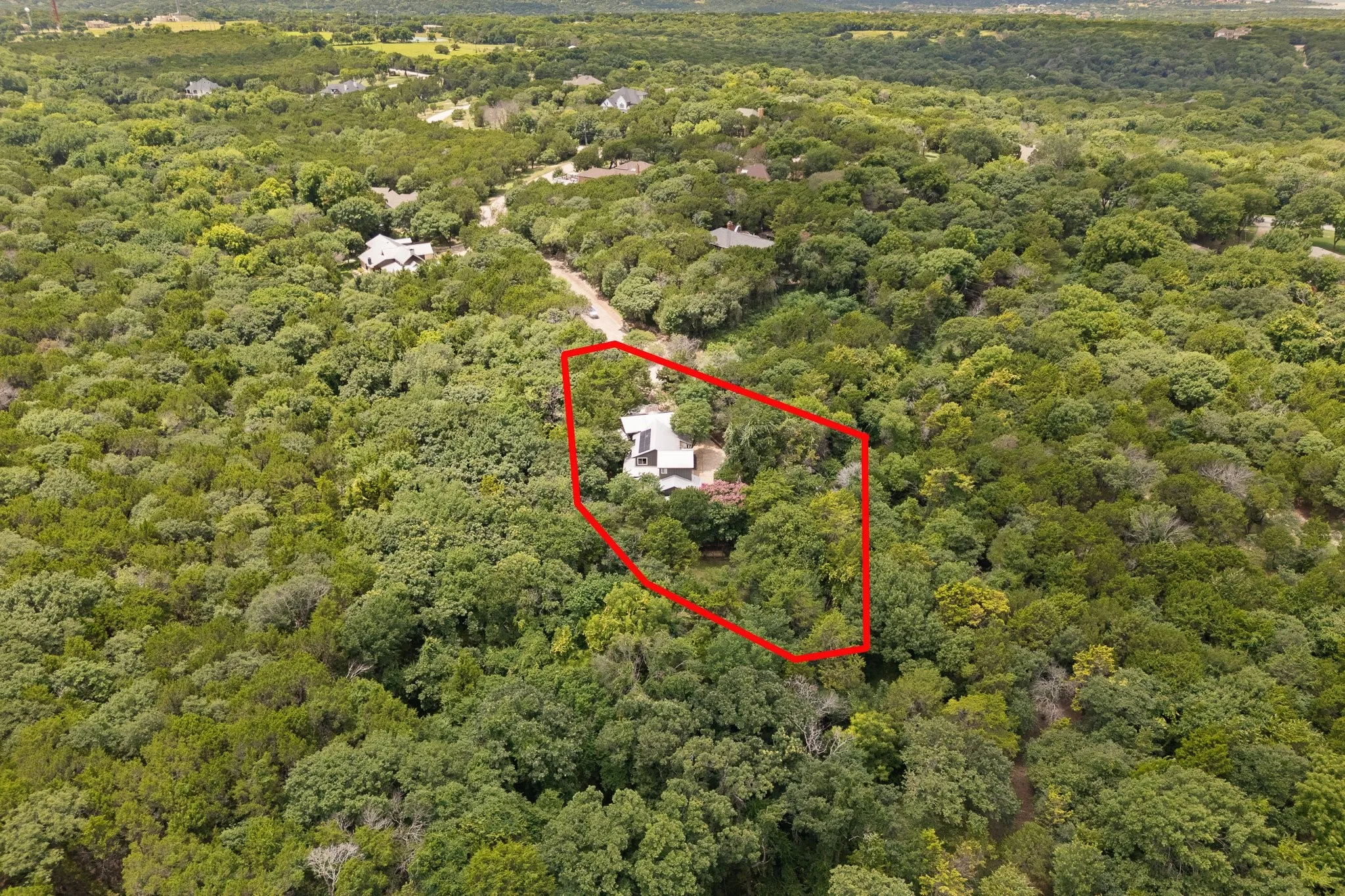 Aerial perspective showcasing a property surrounded by abundant mature trees, offering extensive natural landscaping and the road leading up to the home which is located in a private cul-de-sac
