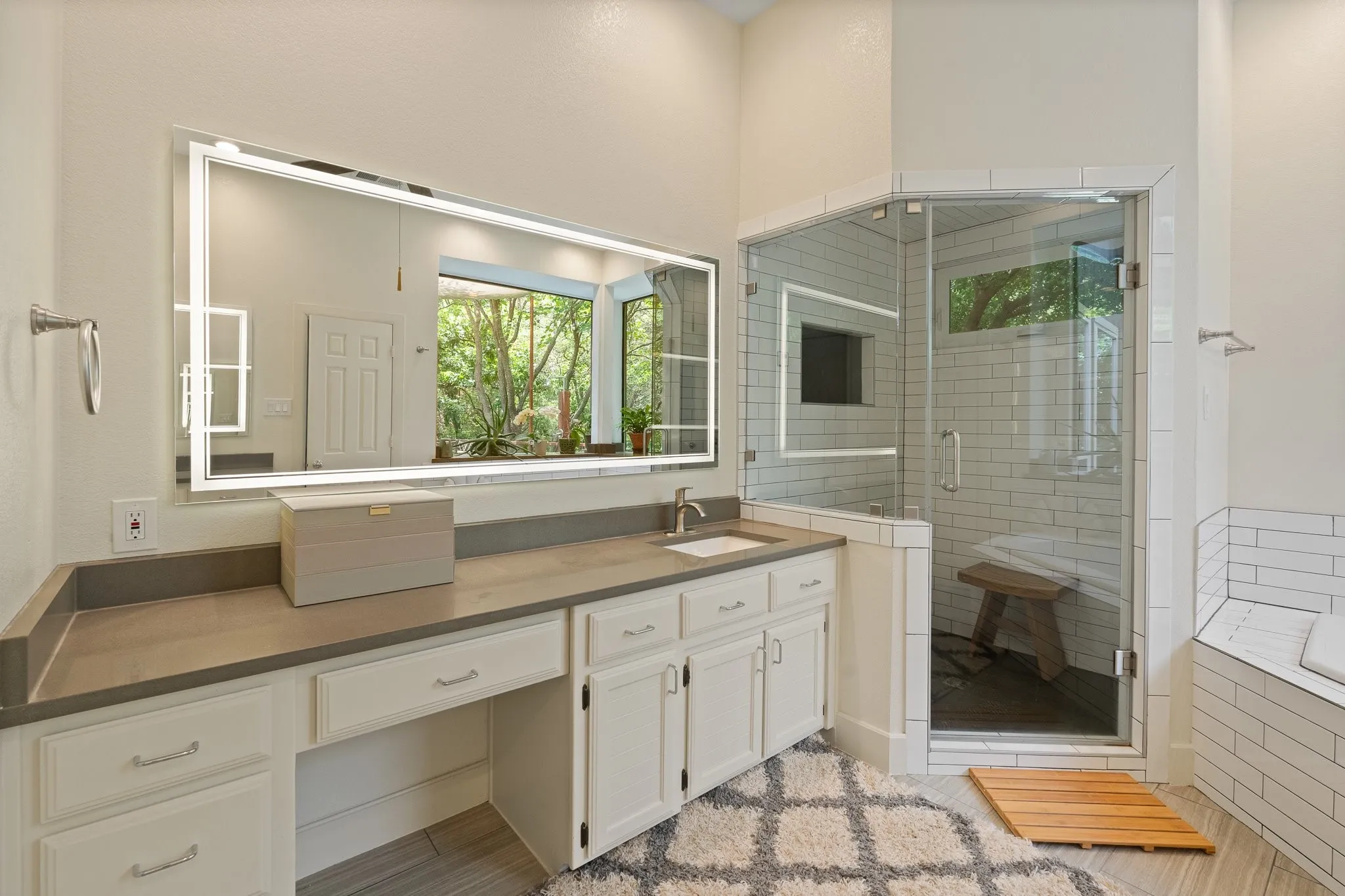 Second individual countertop/sink with large illuminated mirror, walk in shower that features an operable window and steam capability